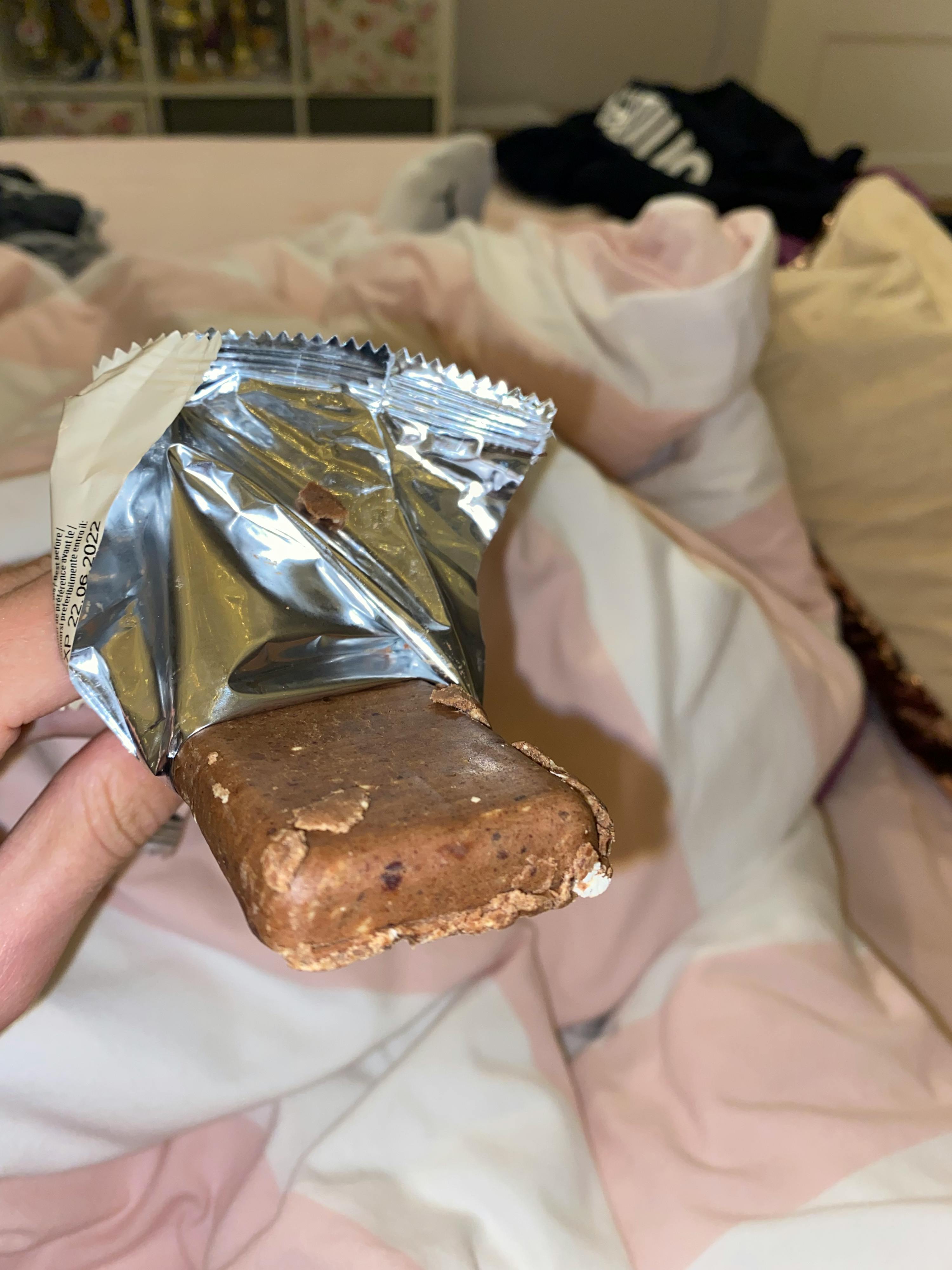 eine Person hält einen Schokoladenriegel in einer Plastikfolie