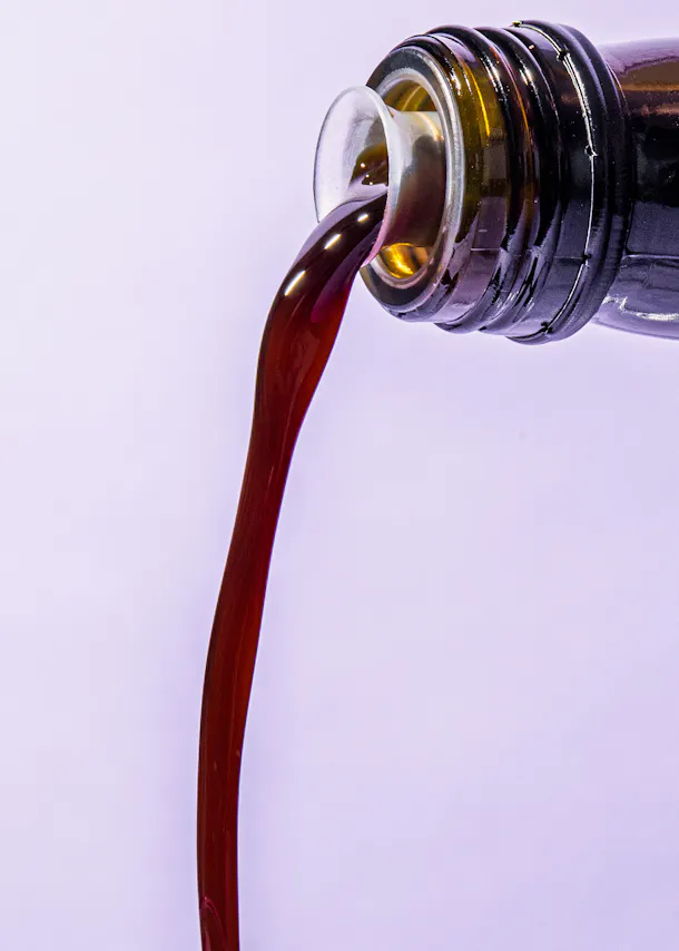 une bouteille de cola est versée sur un fond violet