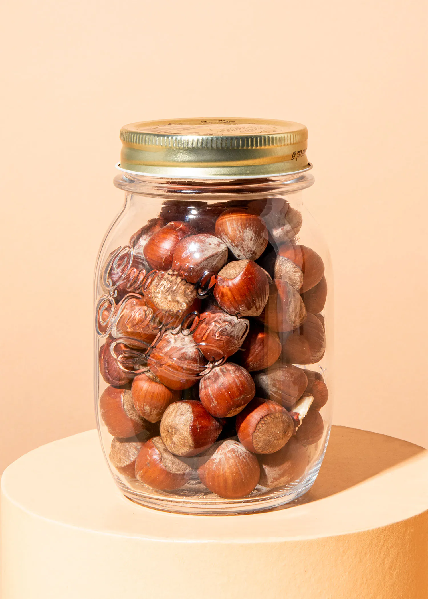ein Glasgefäß voller Haselnüsse mit einem goldenen Deckel