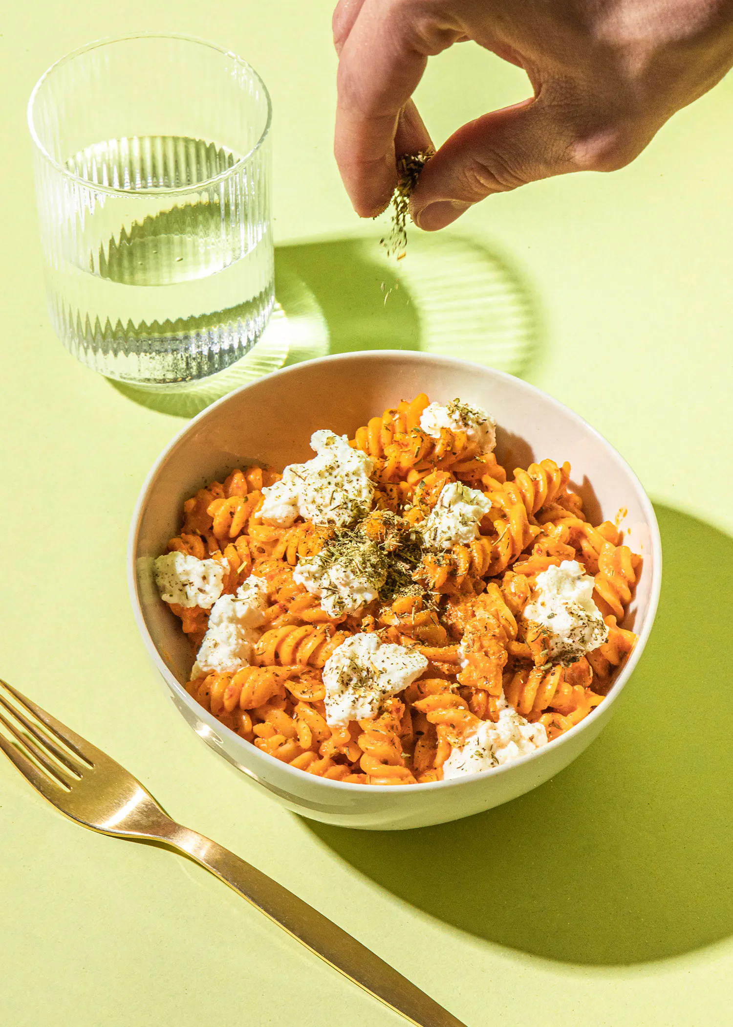 un bol de pâtes avec une fourchette et un verre d' eau à côté