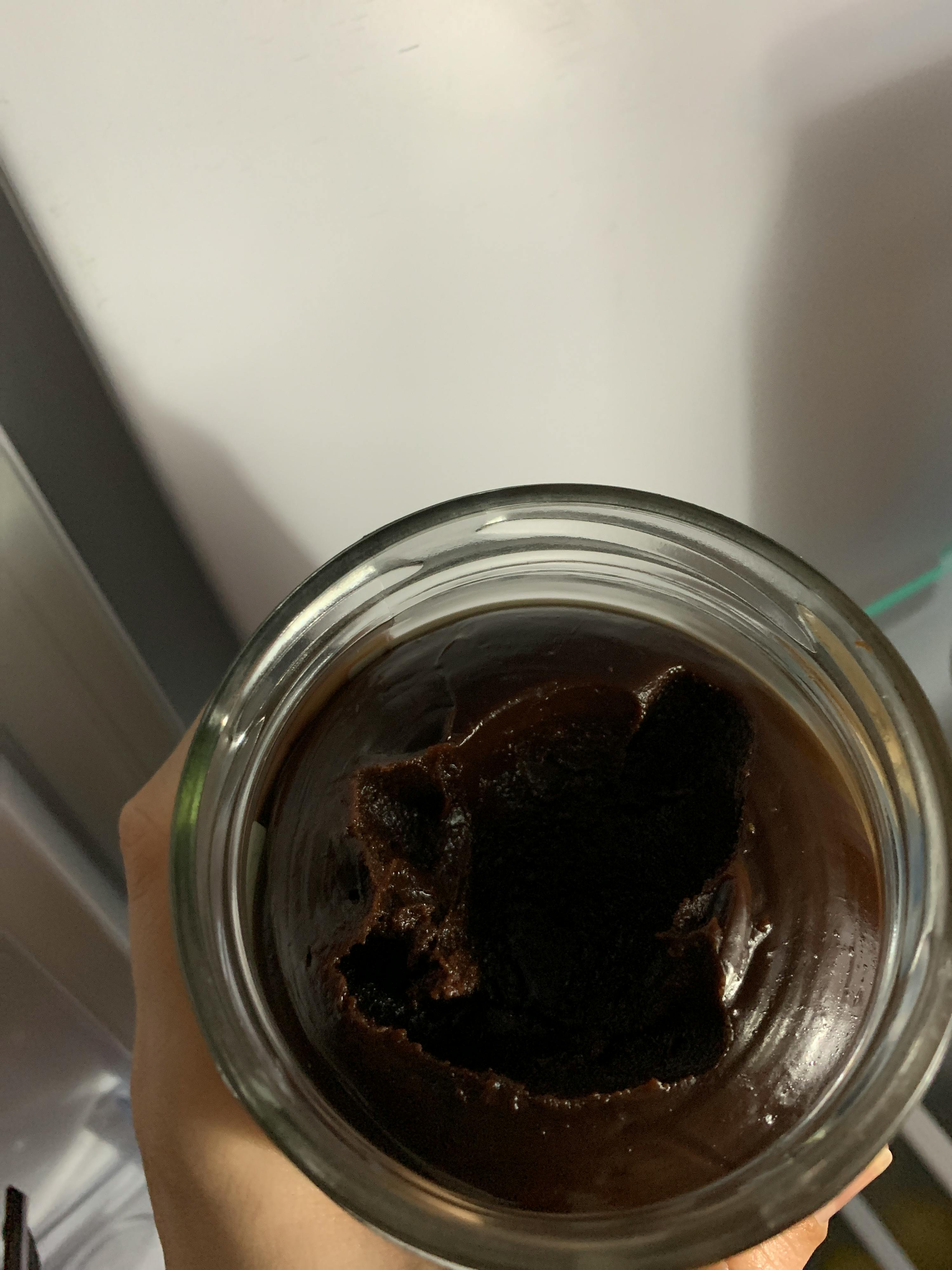 a person is holding a glass jar of chocolate pudding
