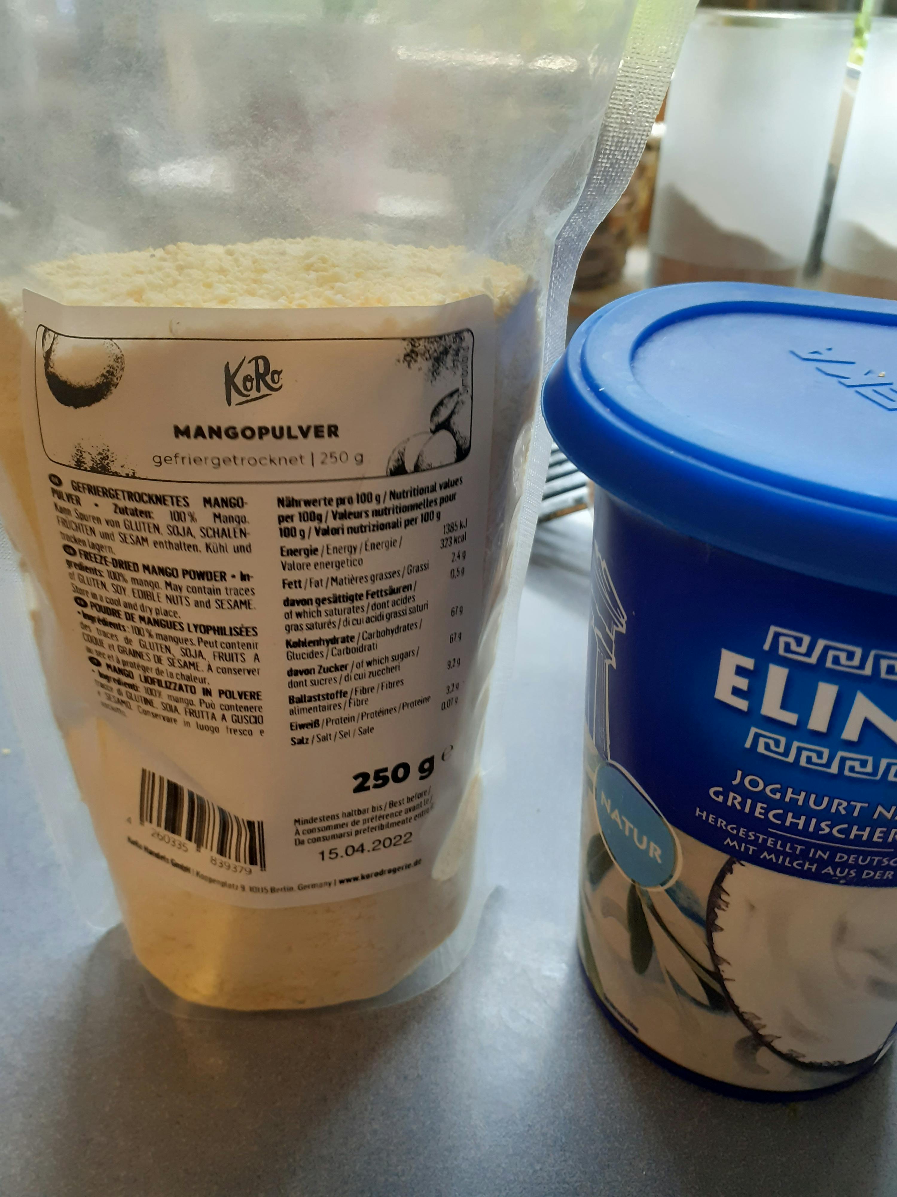 eine Tüte mangopulver steht neben einer Dose griechischem Joghurt
