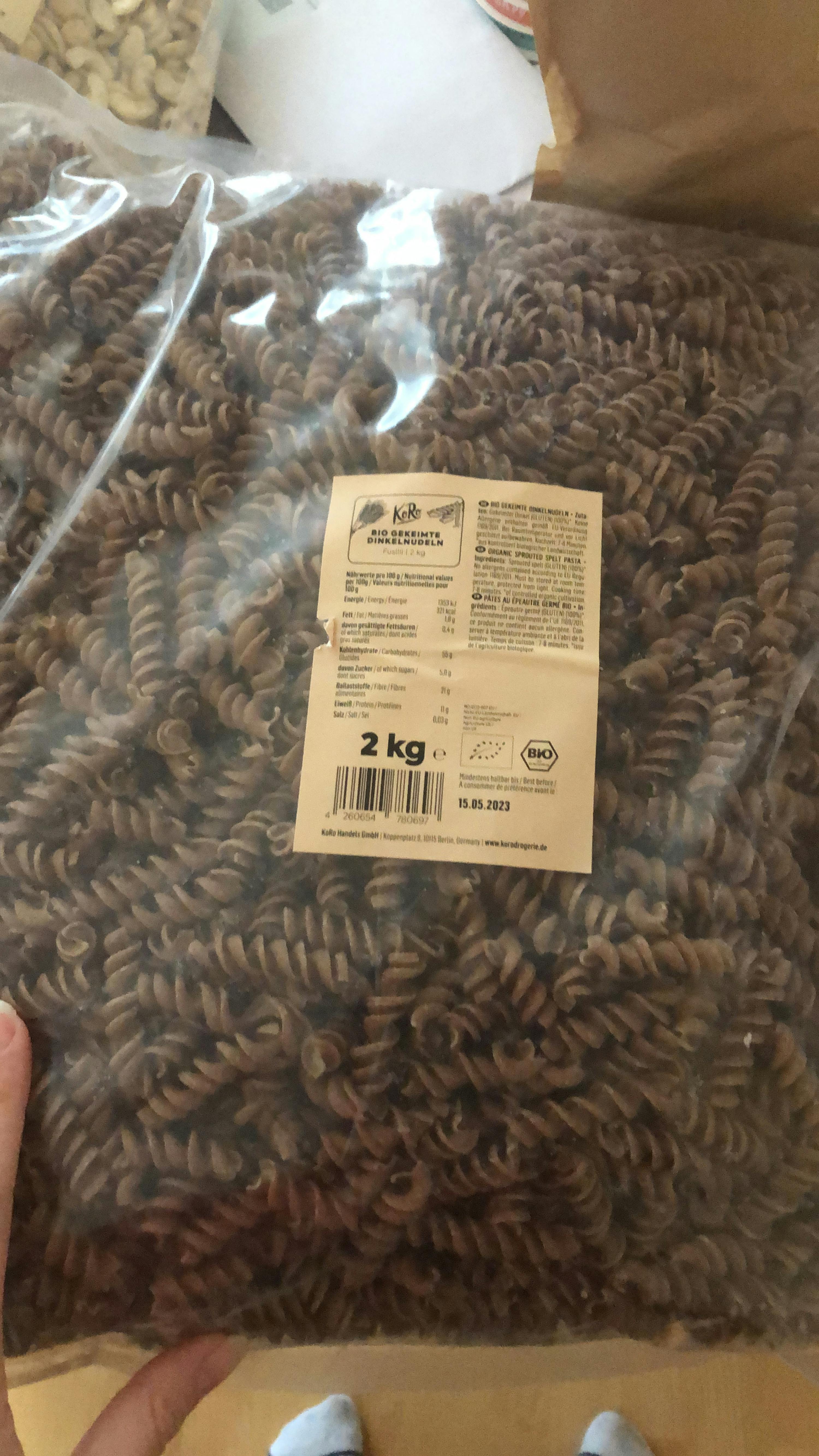 Eine Person hält eine Tüte Nudeln mit einem Gewicht von 2 kg