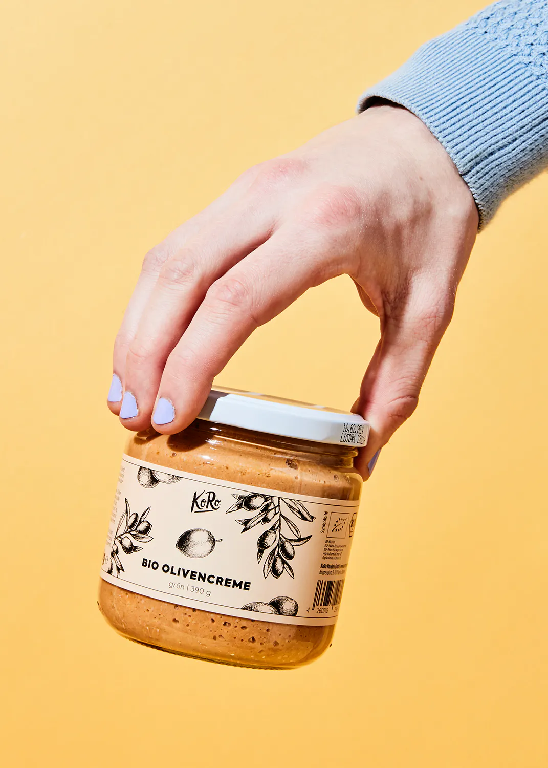 une personne tient un pot de creme d' olives bio