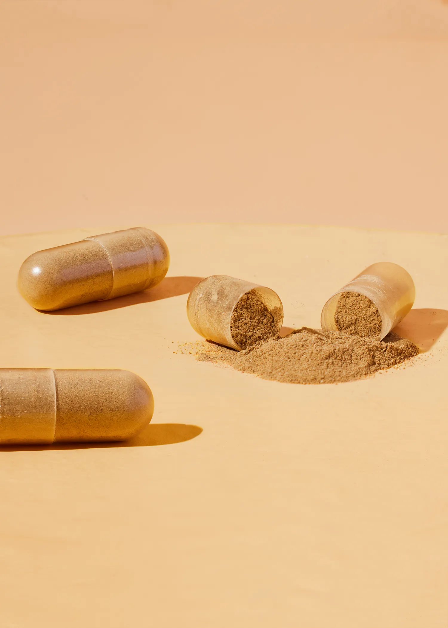 two capsules with powder pouring out of one of them