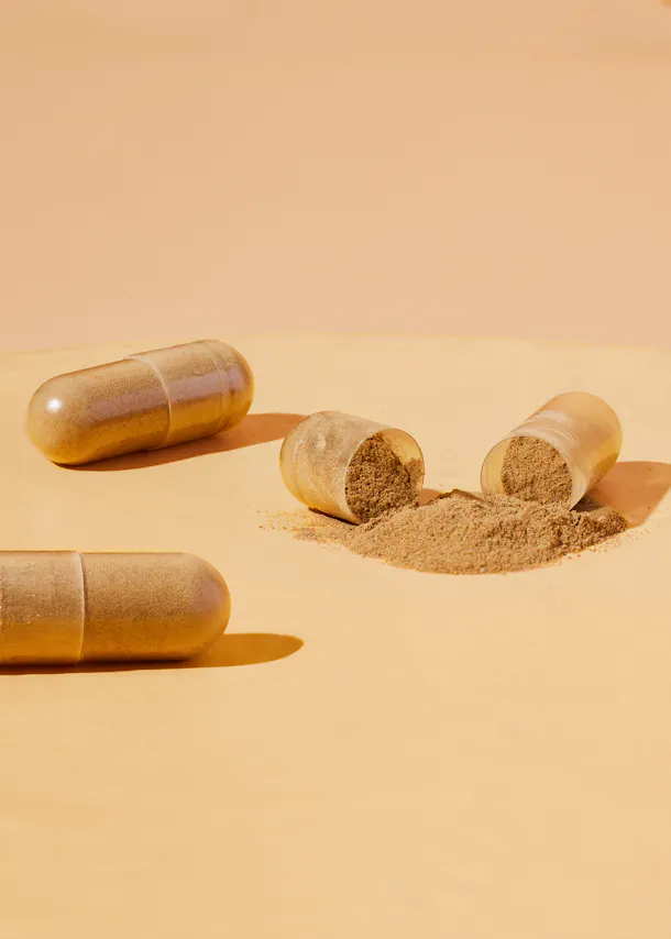 two capsules with powder pouring out of one of them