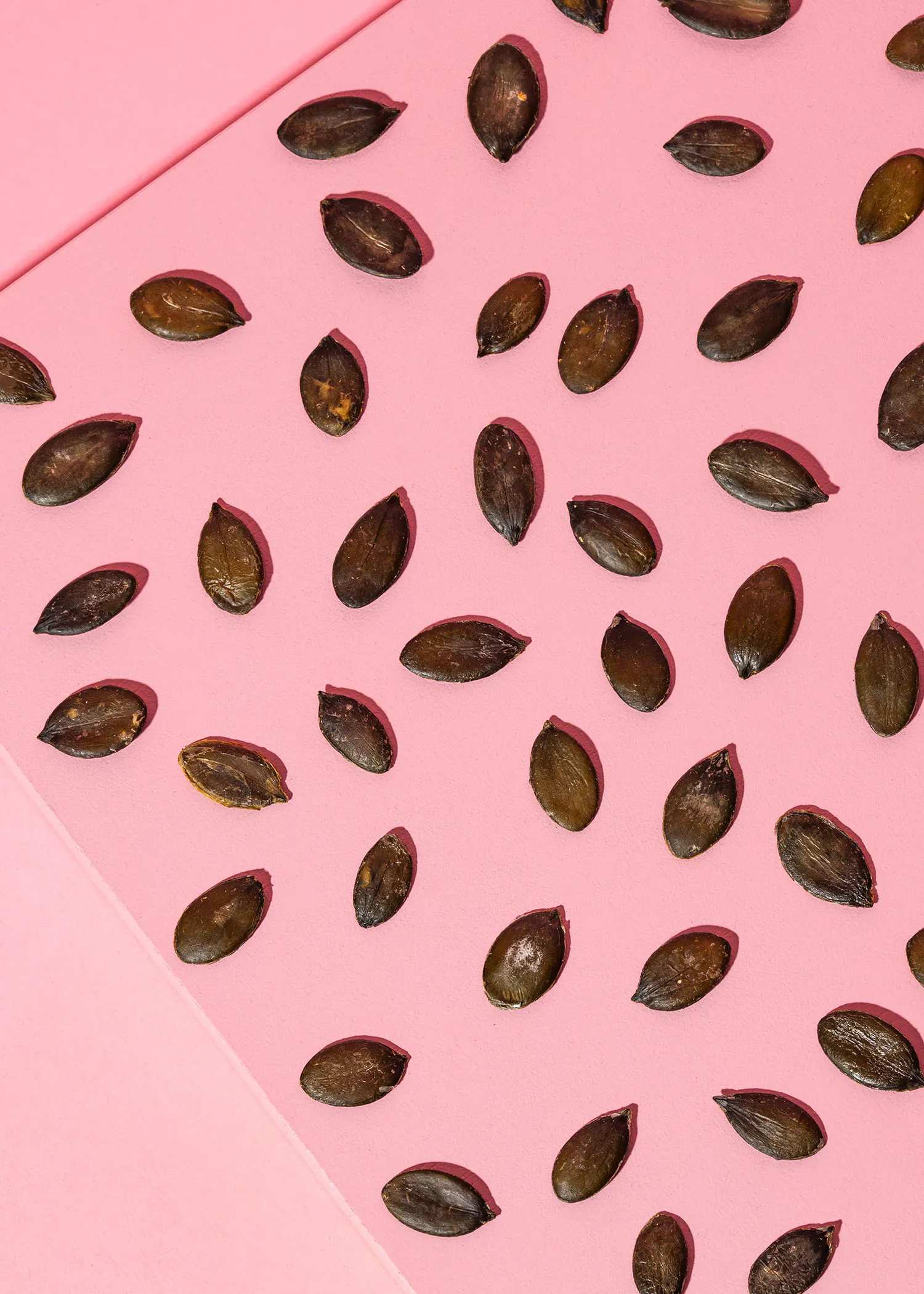 un tas de graines de citrouille sur un fond rose