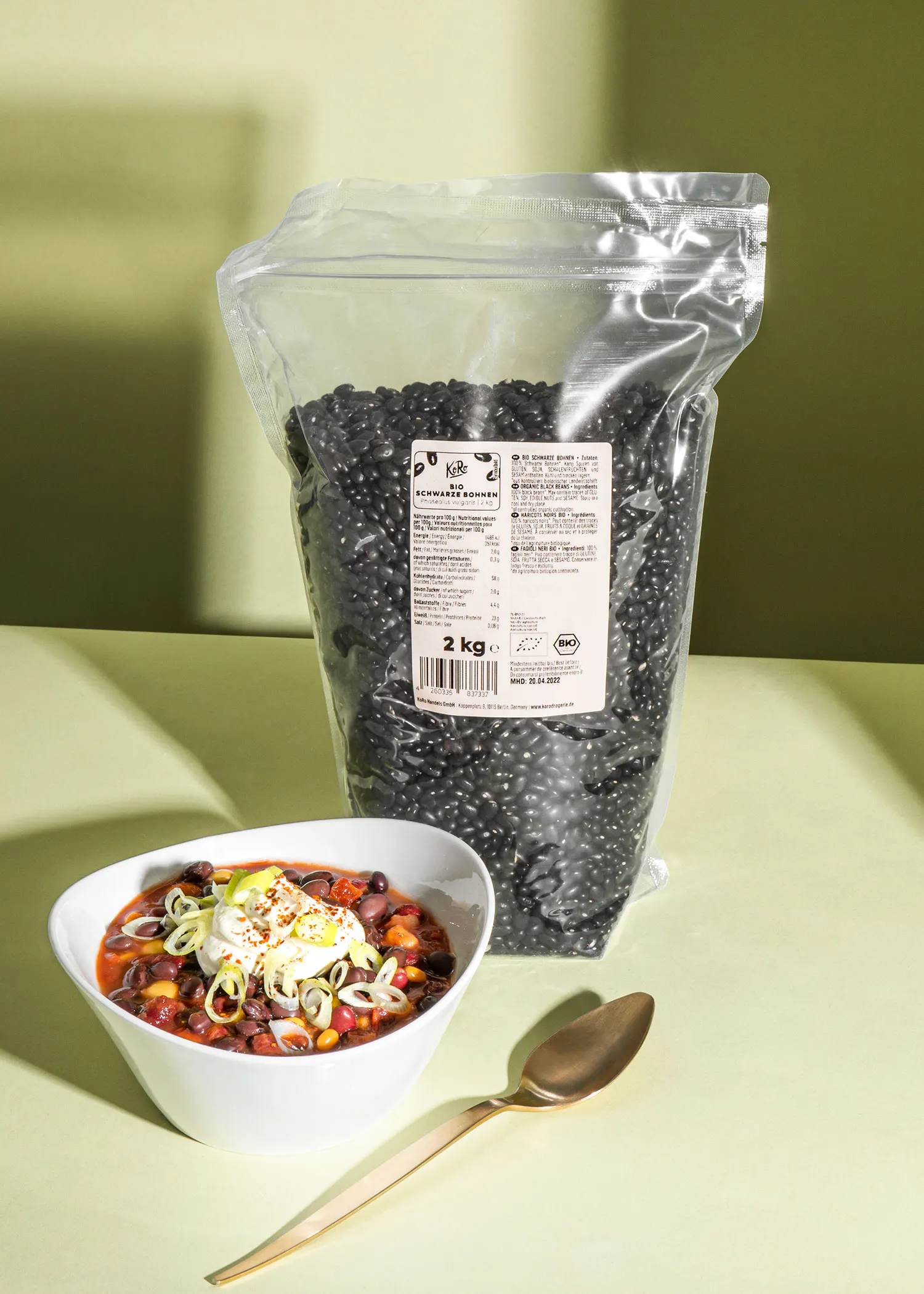 a bowl of chili next to a bag of black beans