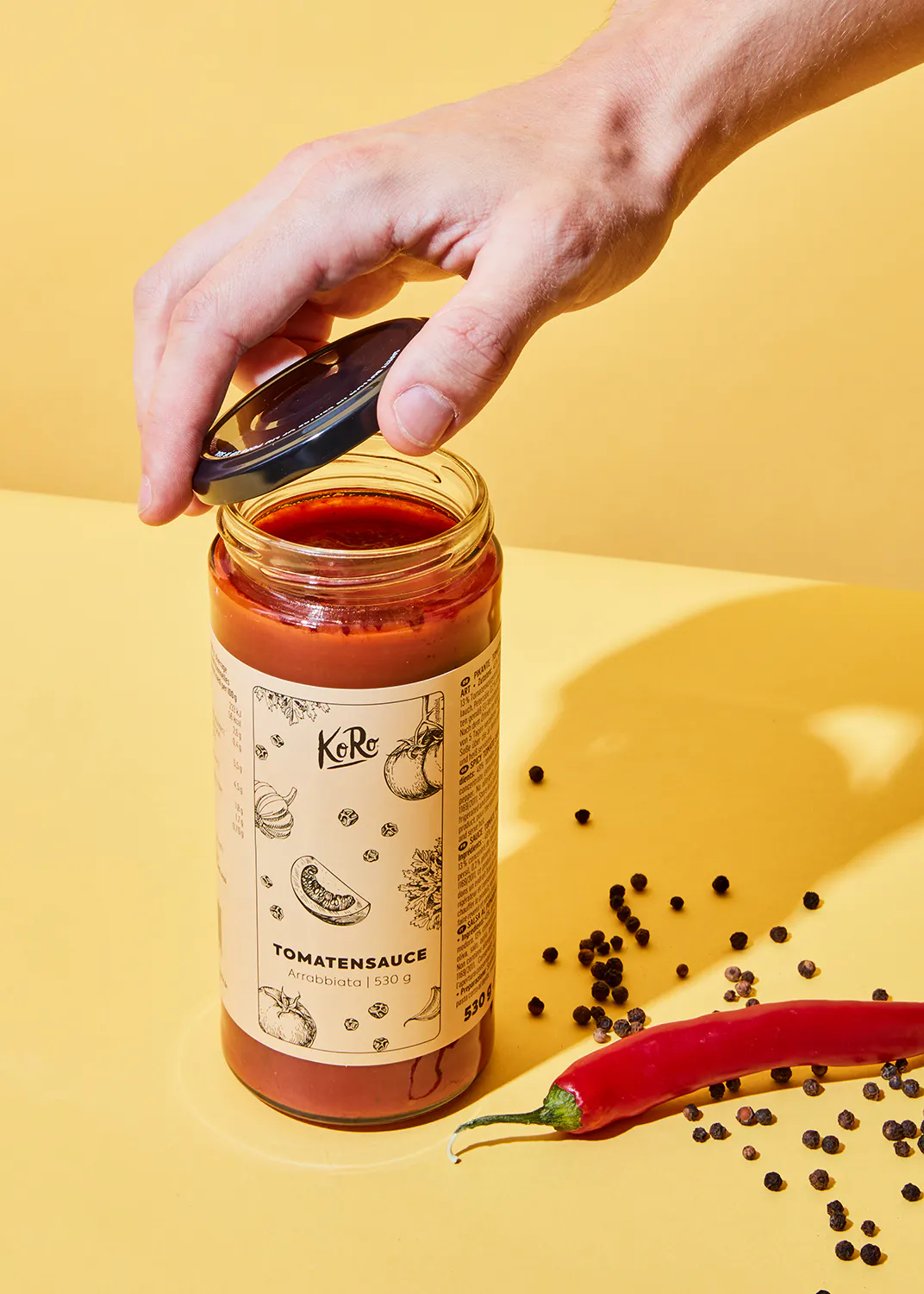 une personne ouvre un bocal de sauce tomate avec un couvercle