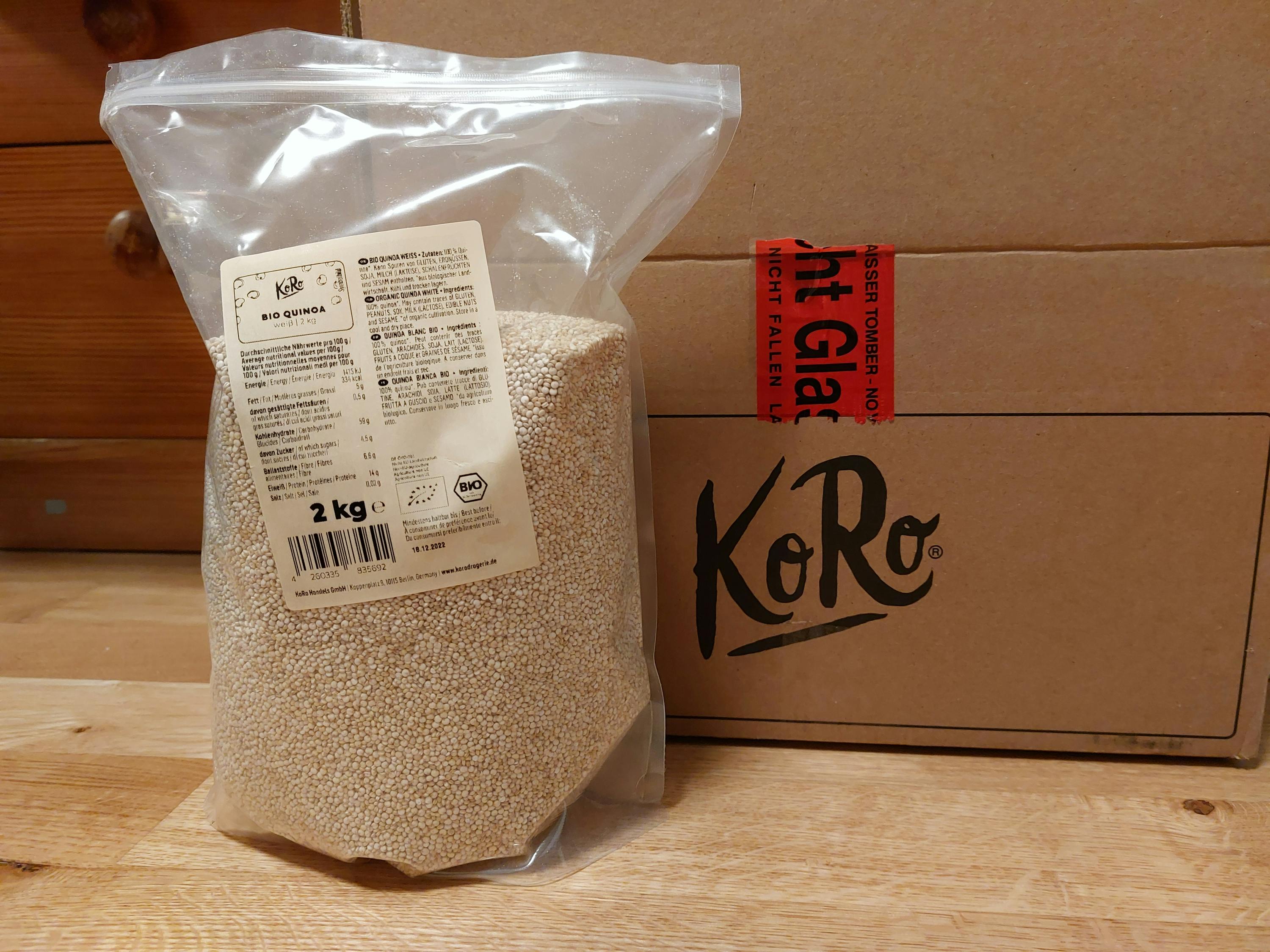 eine Plastiktüte mit 2 kg quinoa steht neben einem Koro-Karton