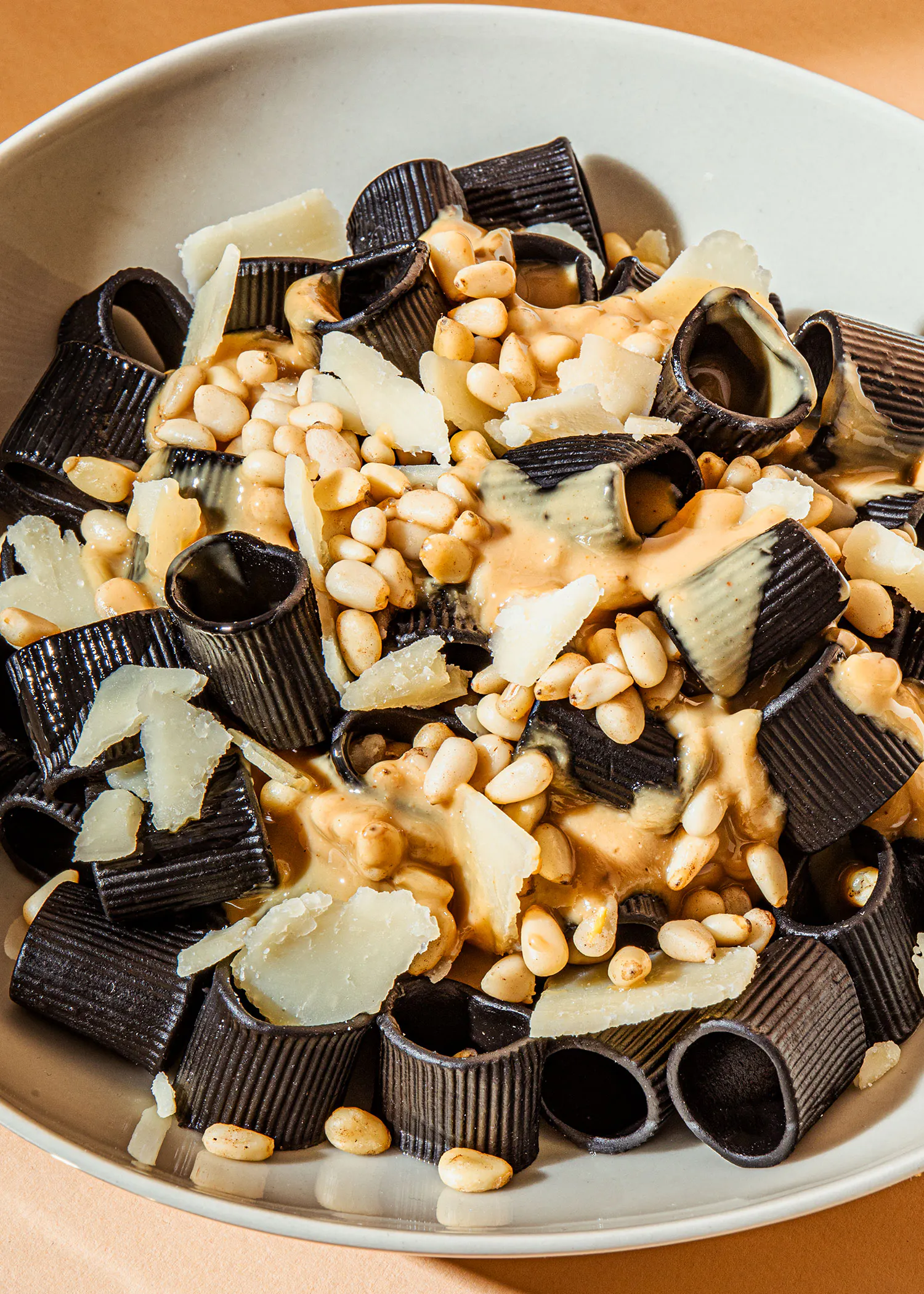 a bowl of pasta with pine nuts and cheese