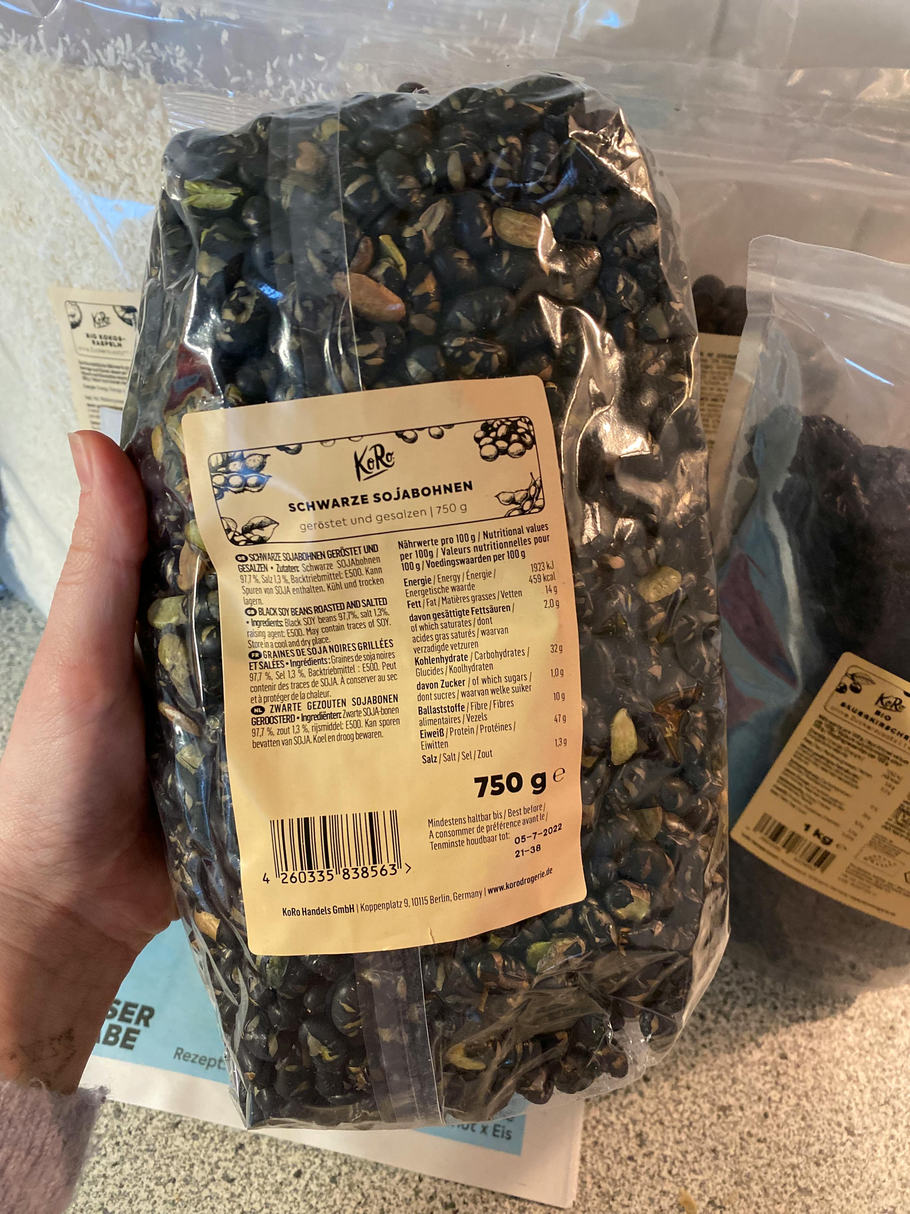 Eine Person hält eine Tüte schwarze Bohnen in der Hand
