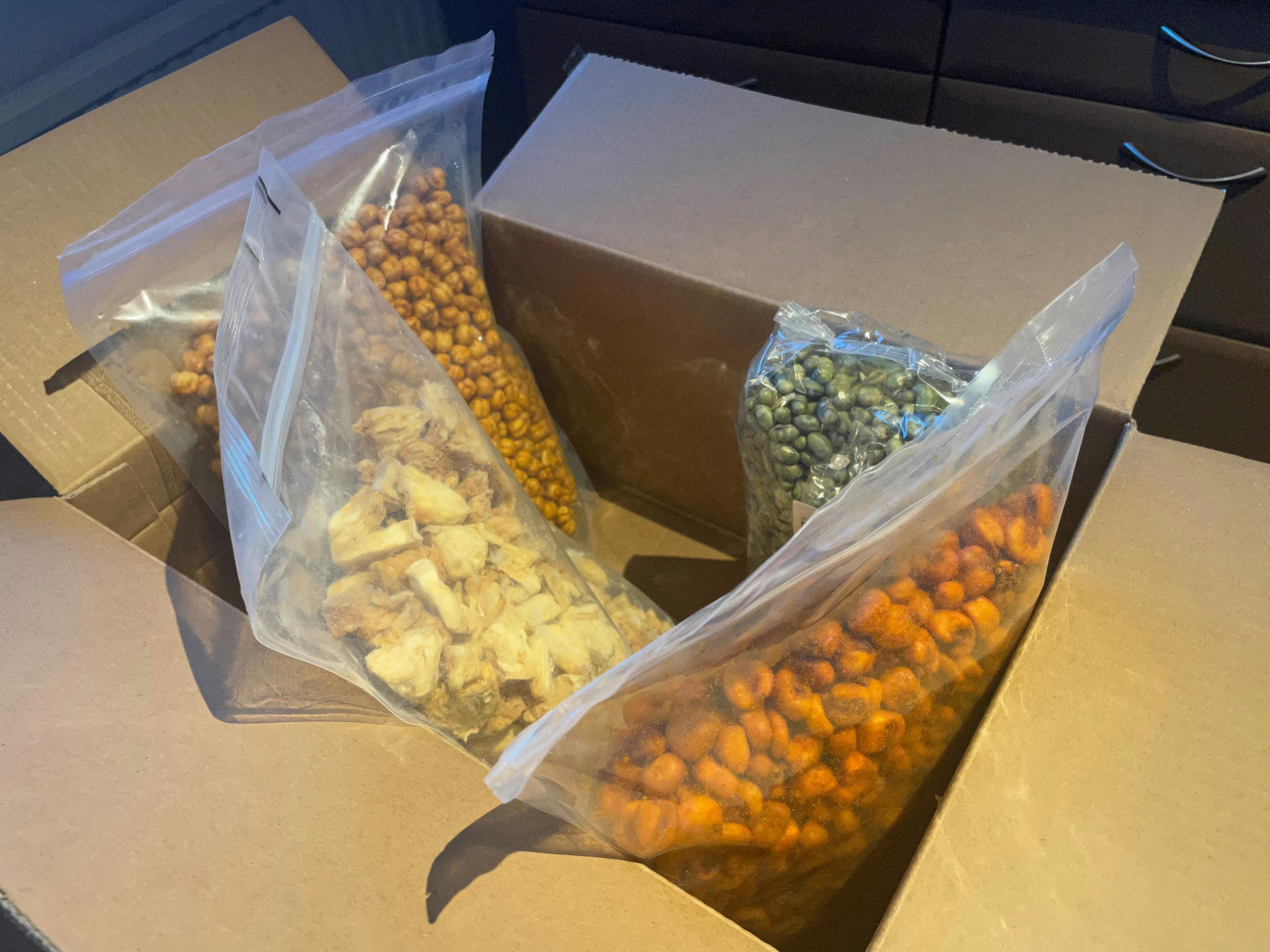 trois sacs de nourriture sont assis à l' intérieur d' une boîte en carton