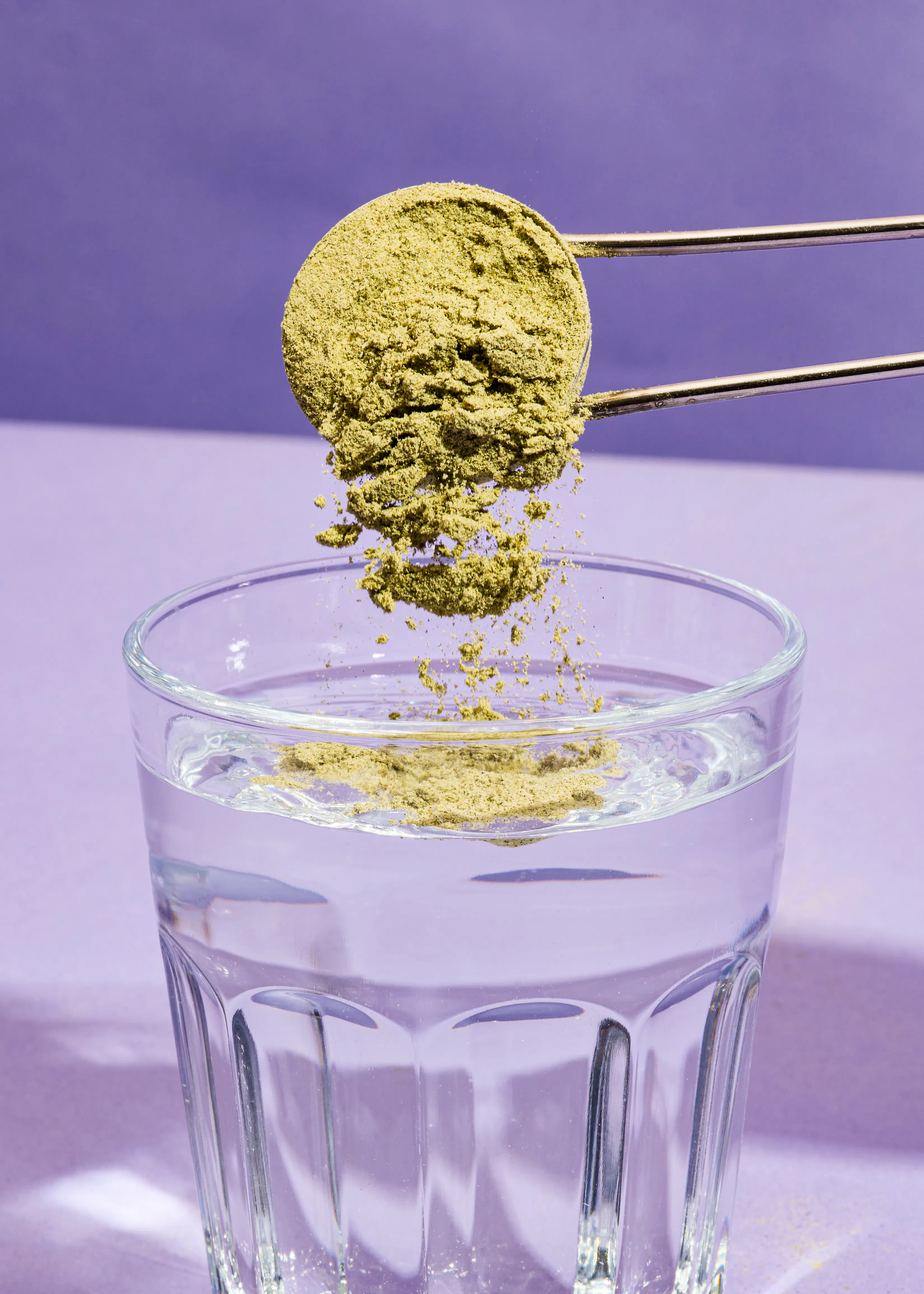 eine Schüssel mit Pulver wird in ein Glas Wasser gegossen