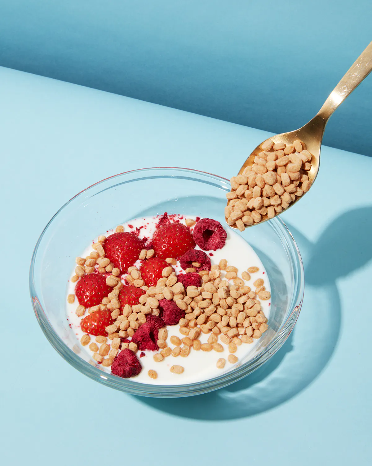 eine Schüssel mit Milch und Müsli mit Himbeeren und Erdbeeren