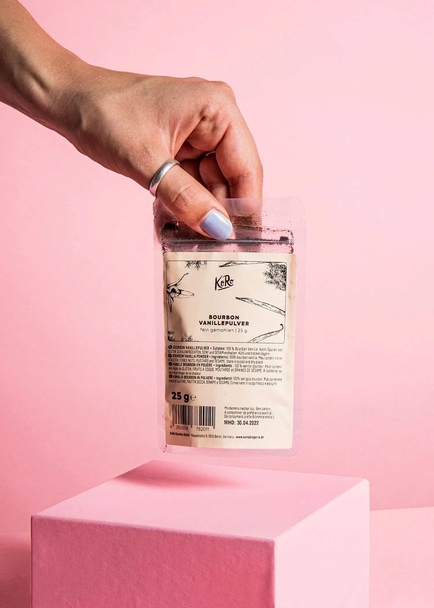 a hand holding a bag of bourbon vanilla powder