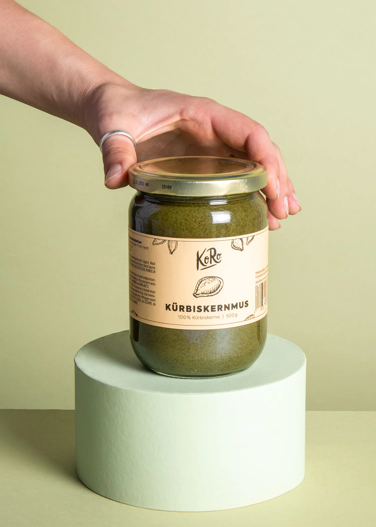 une personne tient un bocal de kurbiskernmus à la main