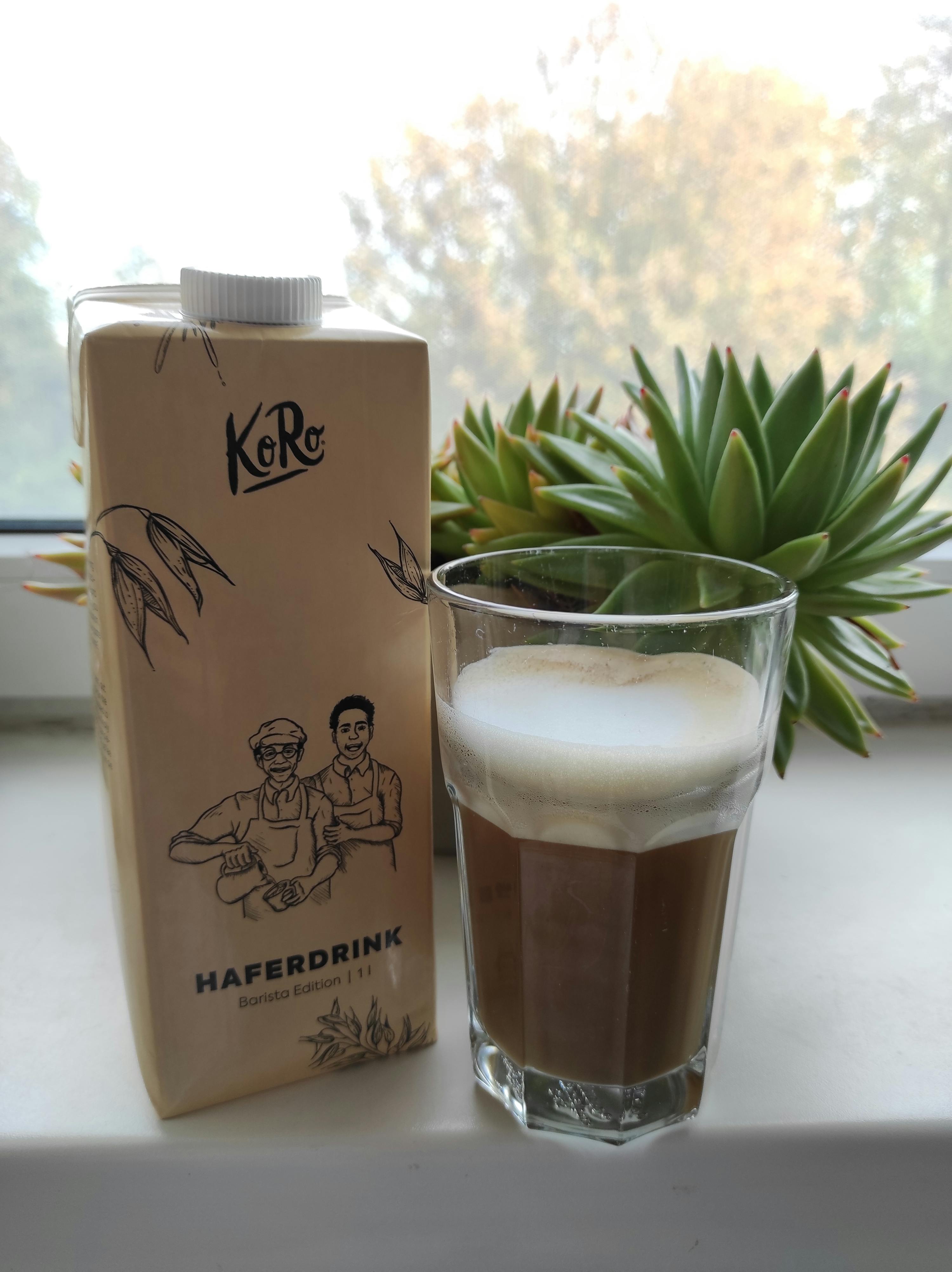 a carton of haferdrink sits next to a glass