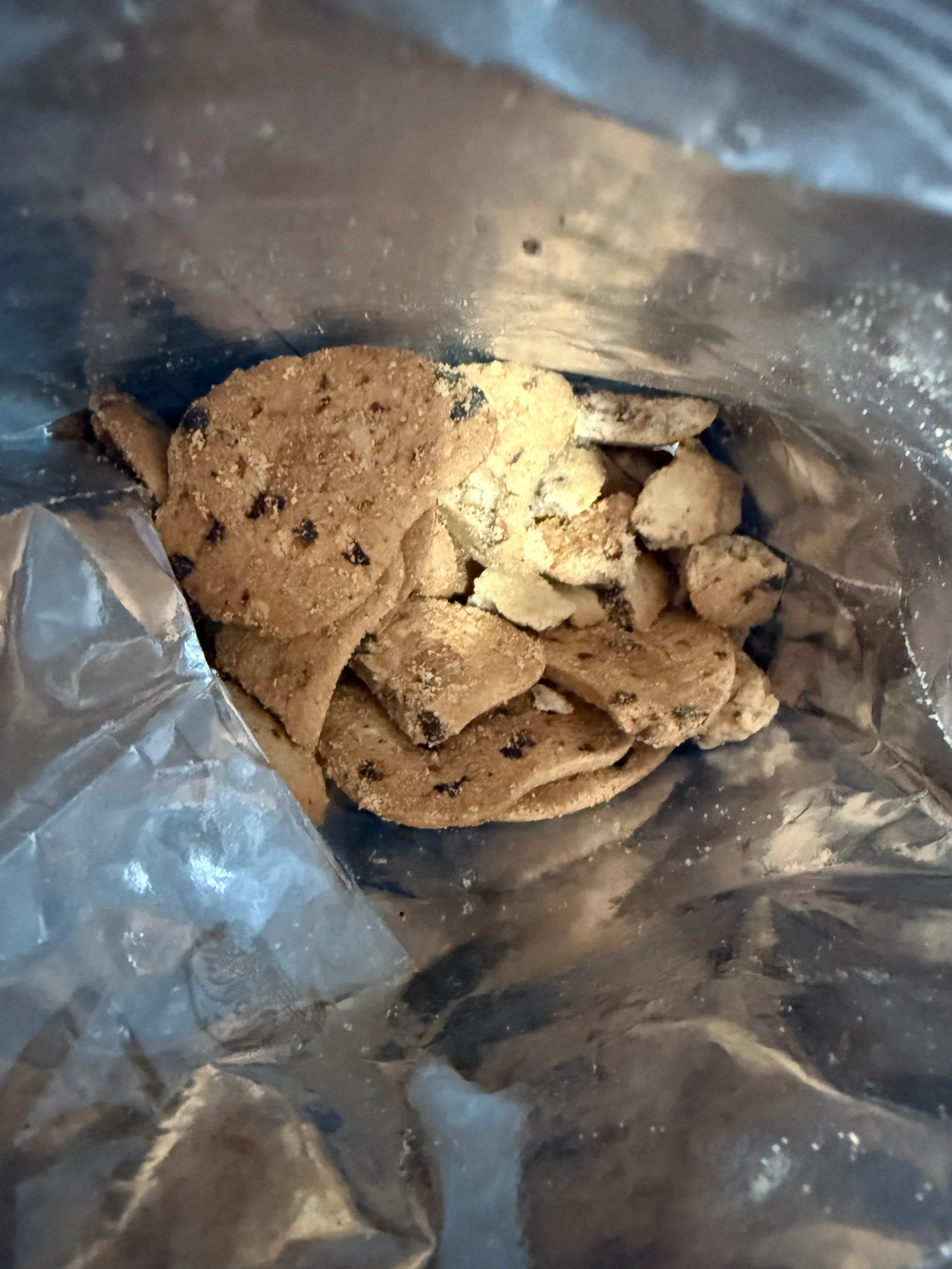 eine nahaufnahme von zerbrochenen schokoladenkeksen und krümeln in einer glänzenden verpackung.