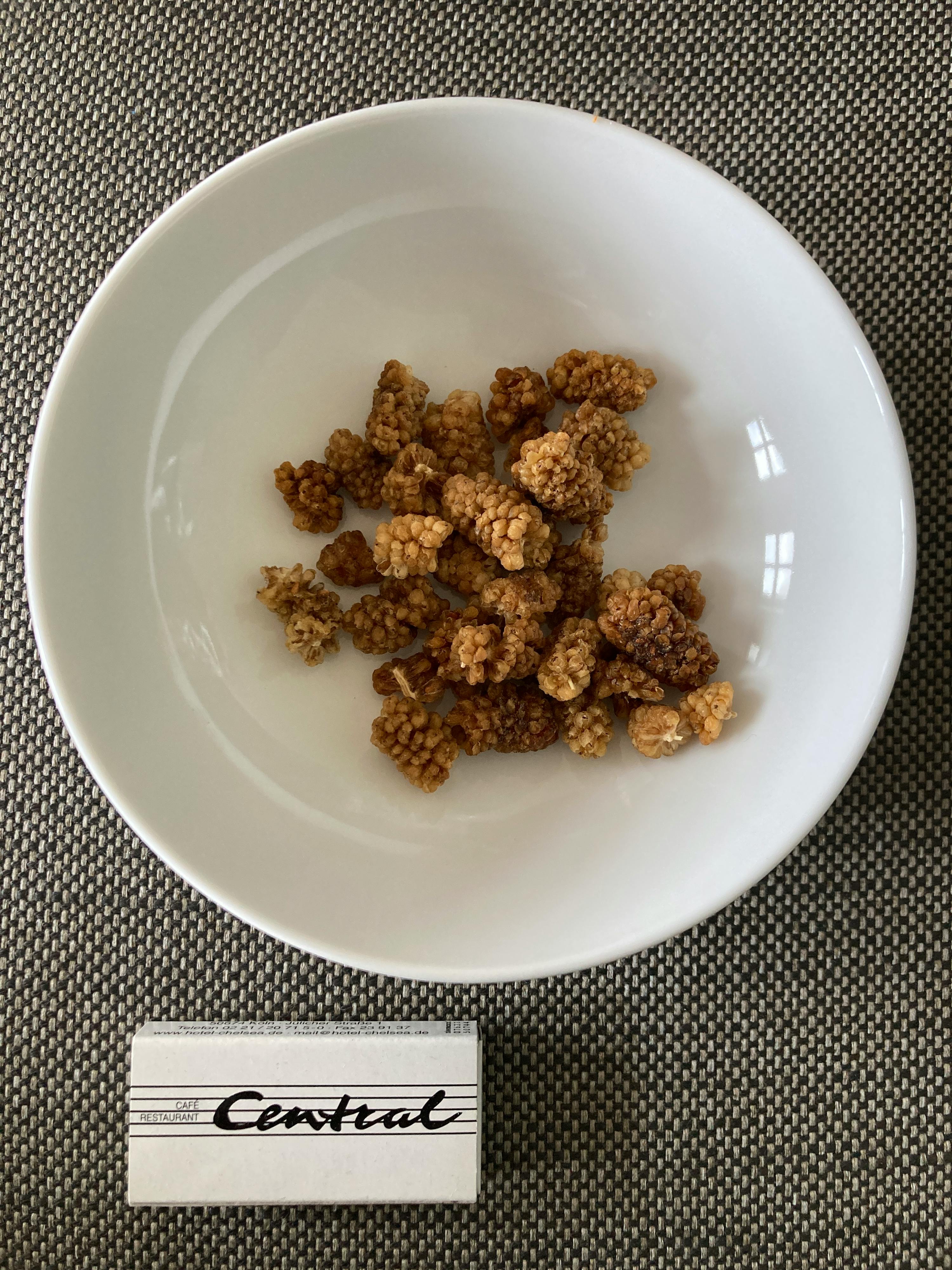 una ciotola di frutta secca è accanto a una scatola di sigarette central