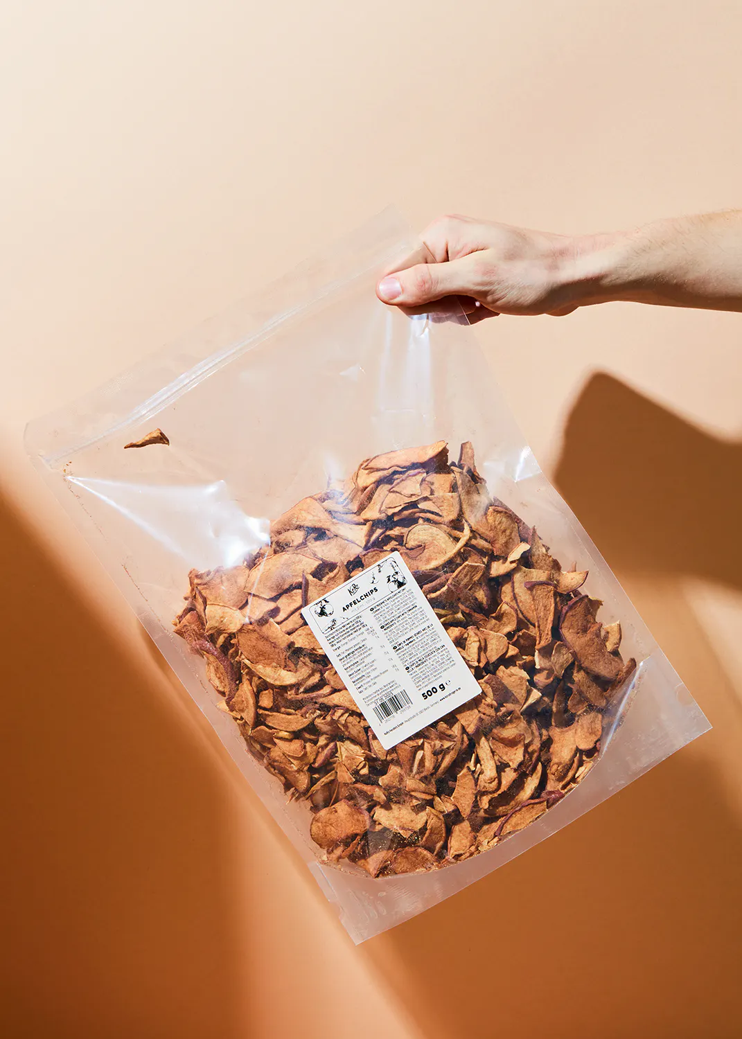 a person is holding a bag of dried apple slices