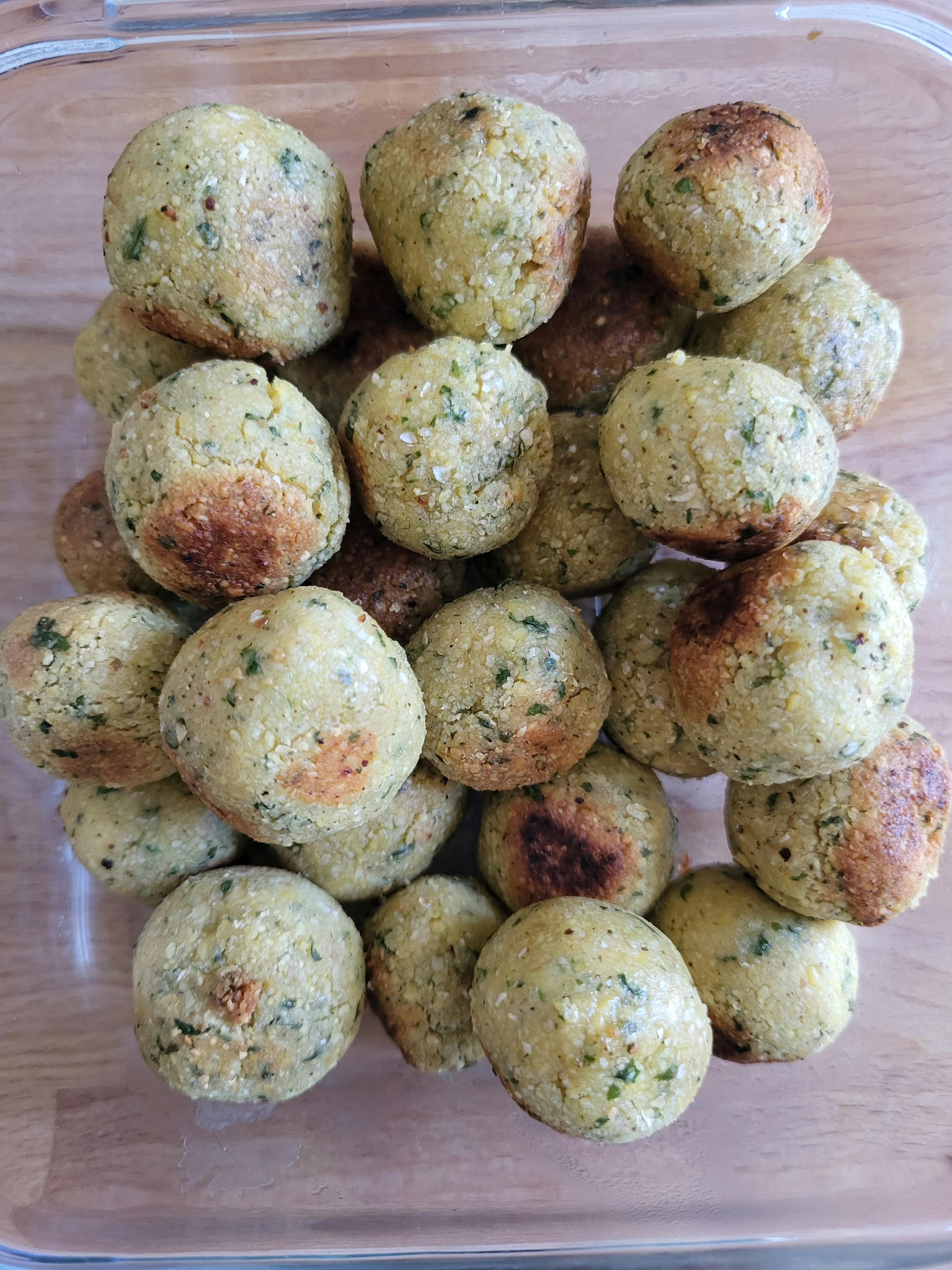 ein Glasgefäß voller falafelbällchen auf einem Holztisch
