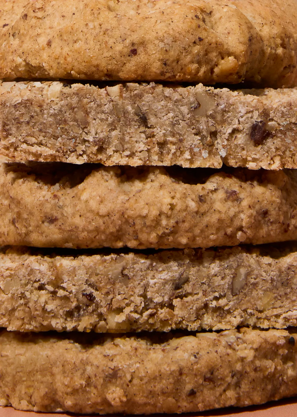 a close-up view of a stack of textured, rustic cookies with visible nuts and grains.
