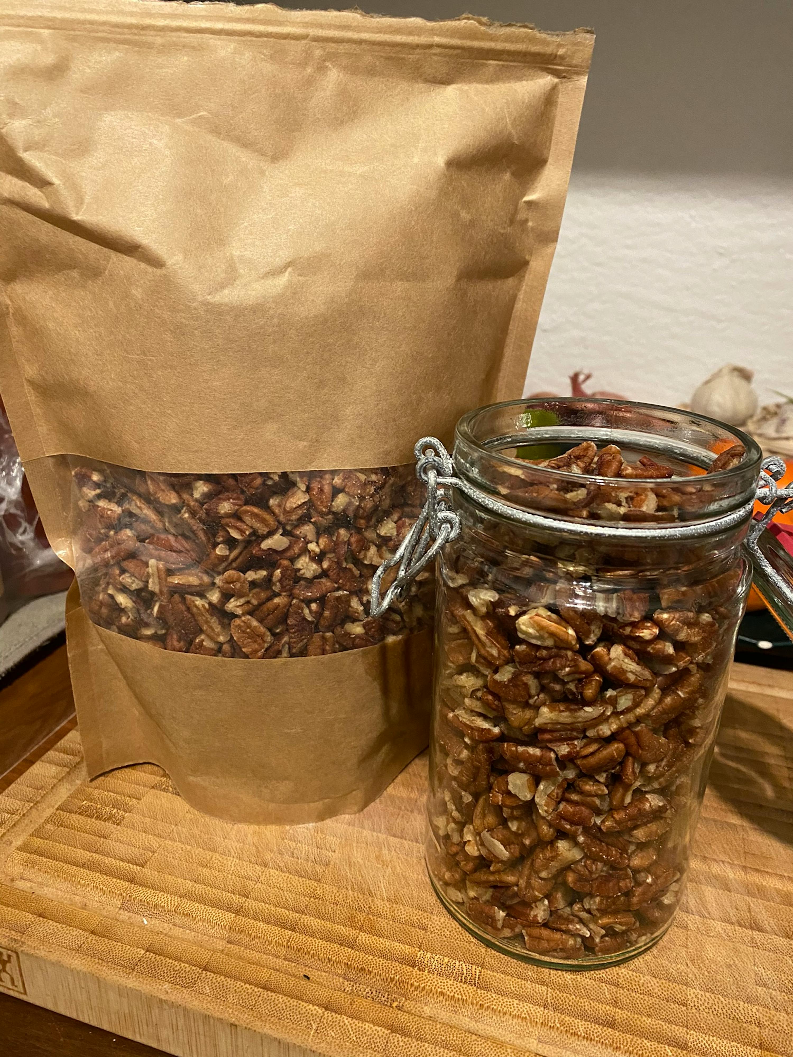 eine Tüte Pistazien neben einem Glas auf einem Schneidebrett