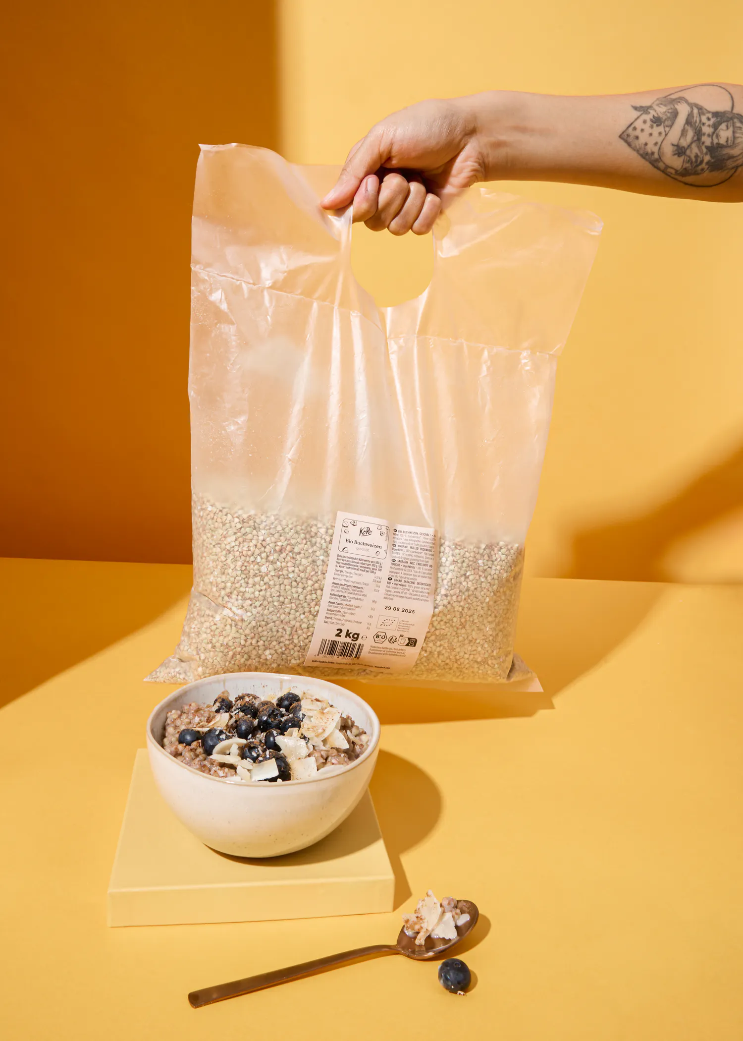 une personne tient un sac de céréales de 2 kg à côté d' un bol de céréales