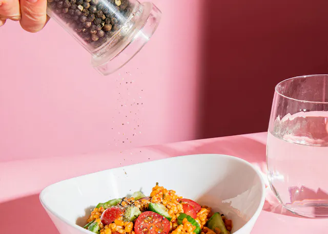 someone is pouring black pepper into a bowl of food