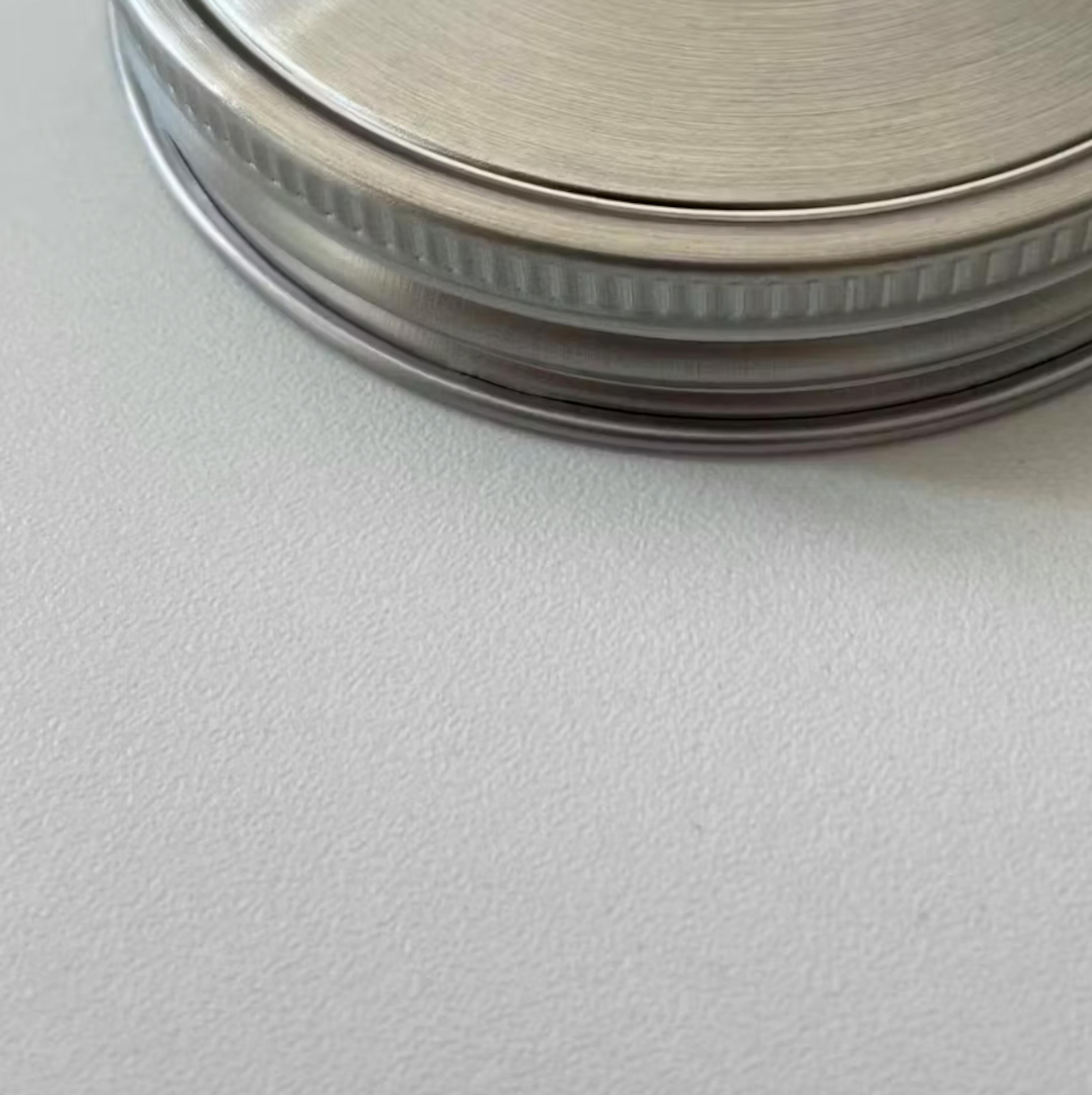 eine Nahaufnahme eines Edelstahldeckels auf einer weißen Oberfläche
