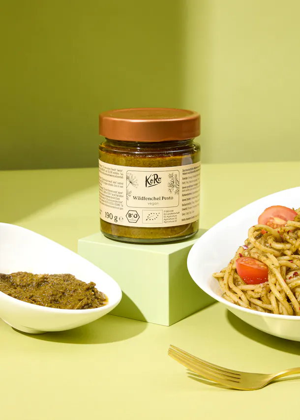 un pot de pesto est assis à côté d' un bol de pâtes