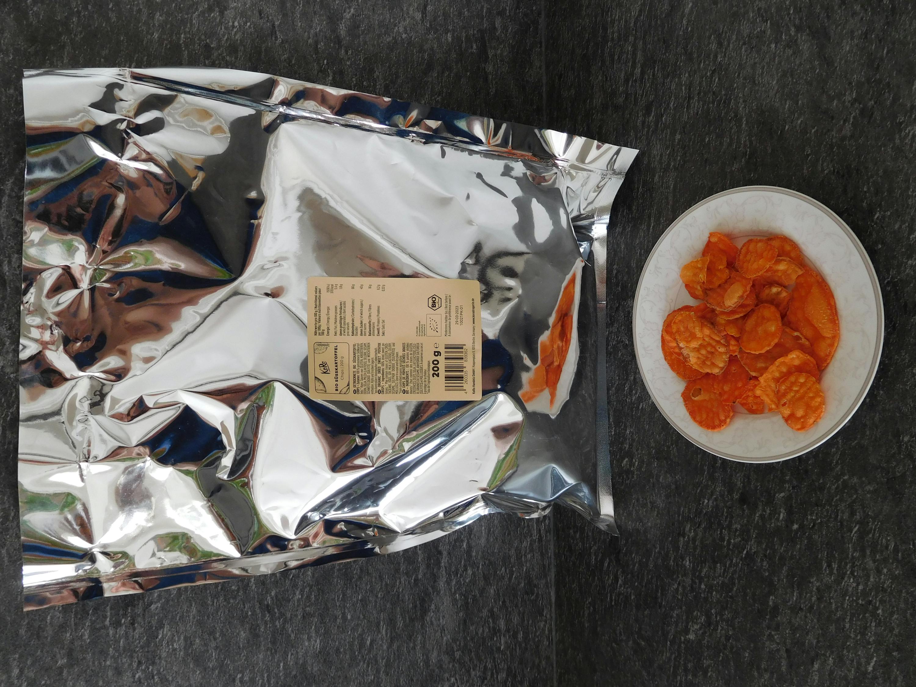 a bag of aluminum foil next to a plate of chips