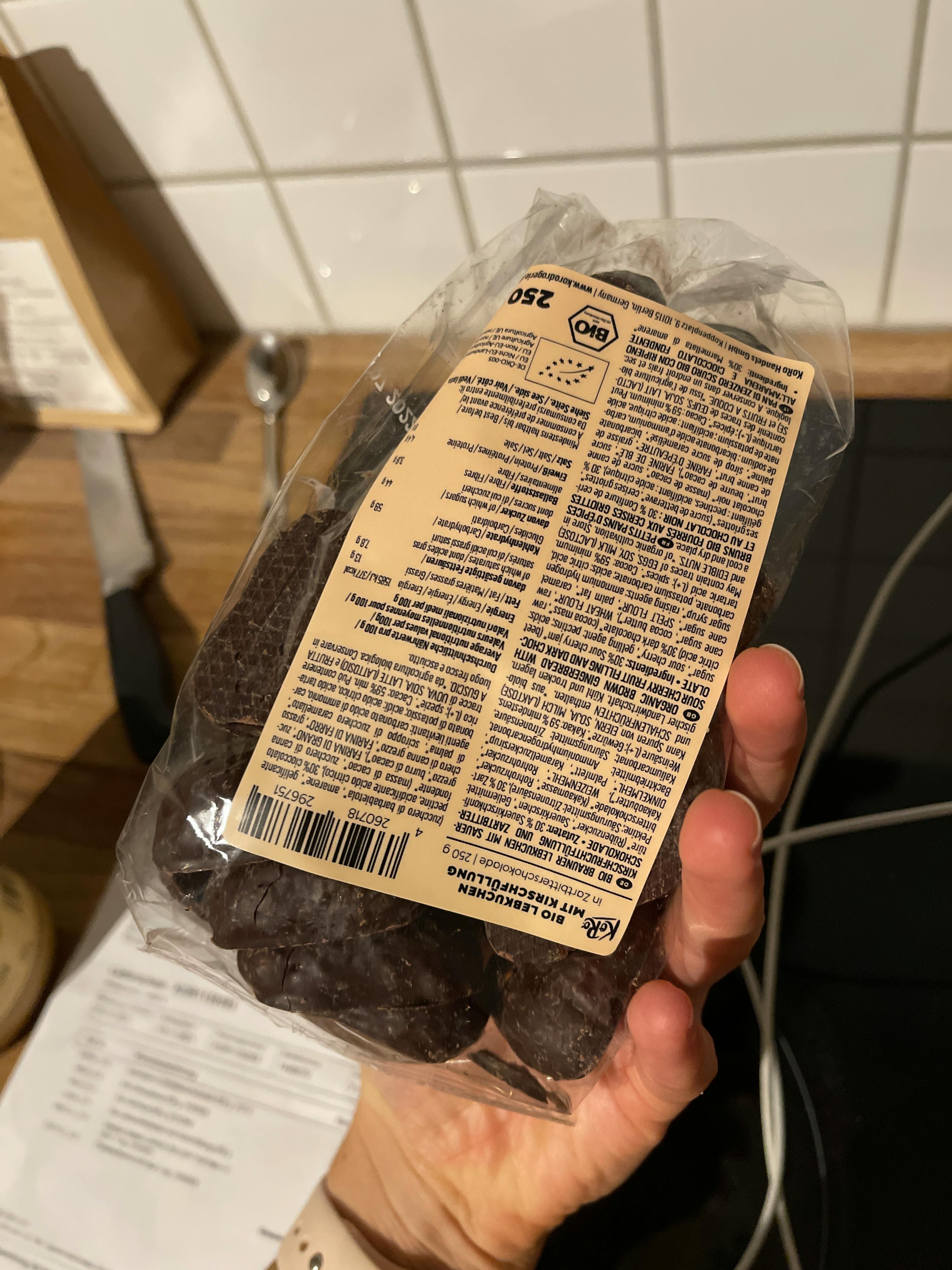 a person is holding a bag of chocolate covered cookies