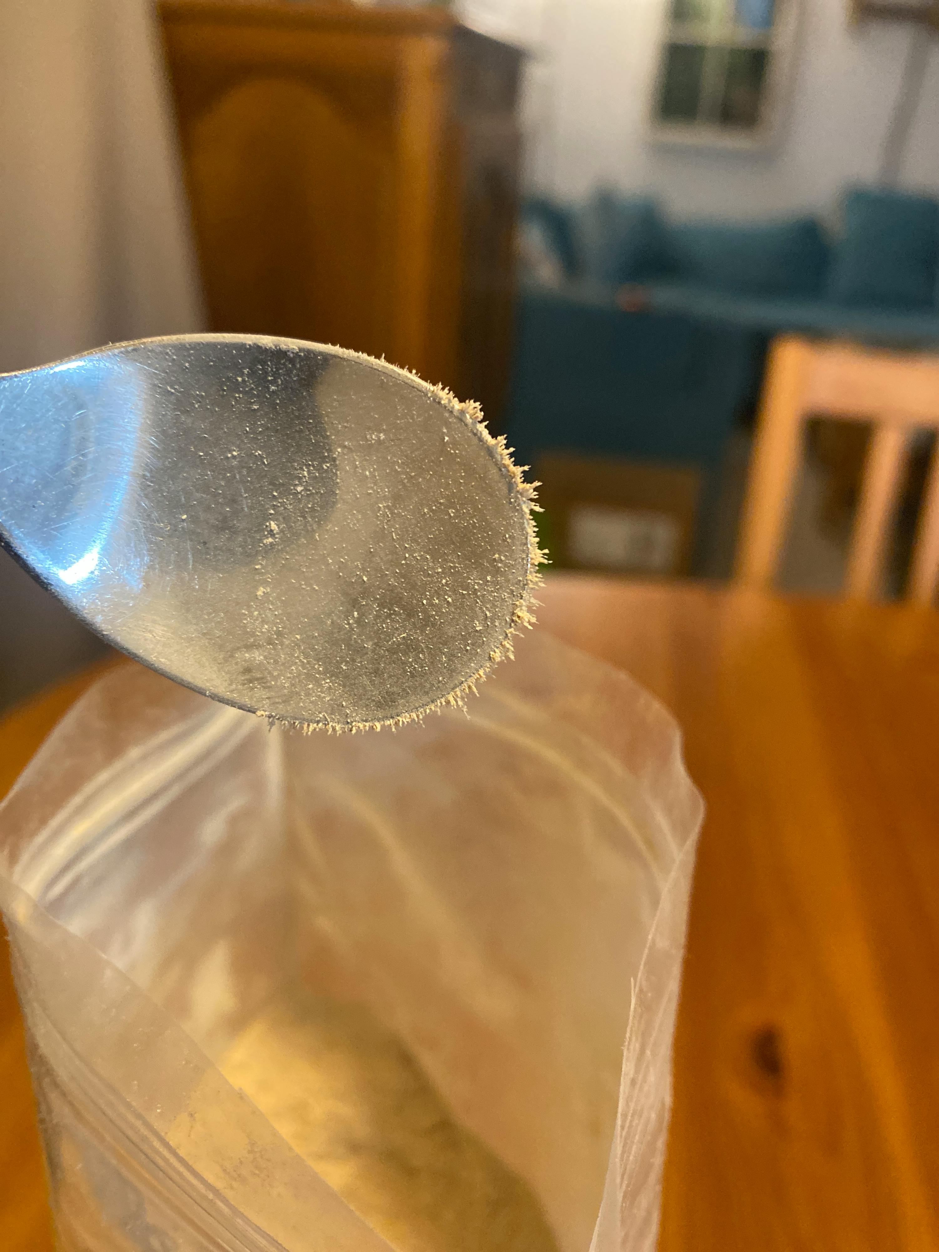 un primo piano di una cucchiaio accanto a un sacchetto di polvere