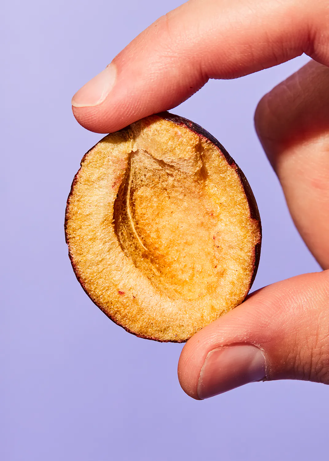 eine Person hält eine halbe Pflaume in der Hand