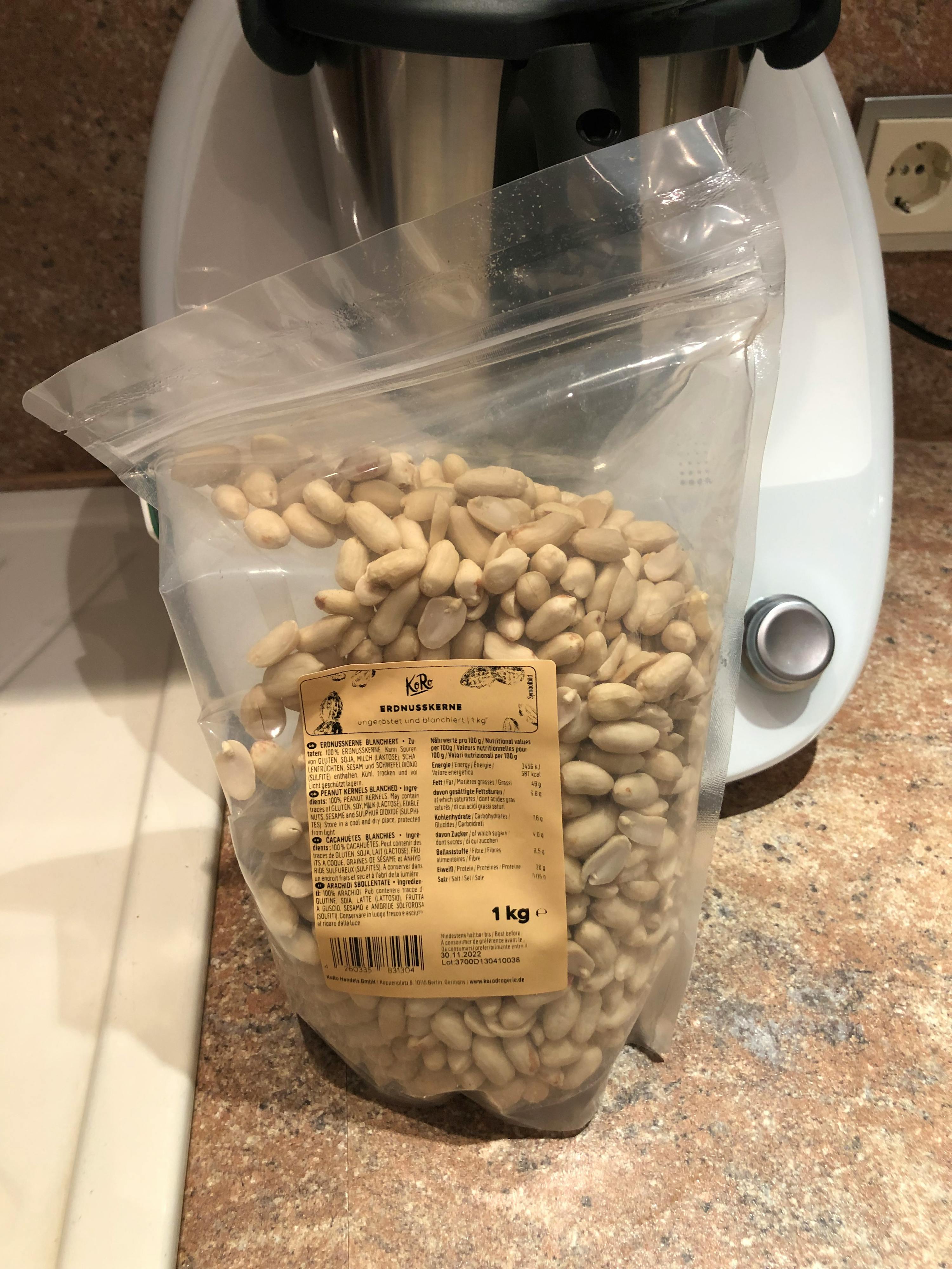 eine Plastiktüte mit Erdnüssen liegt auf einem Tisch neben einem Mixer