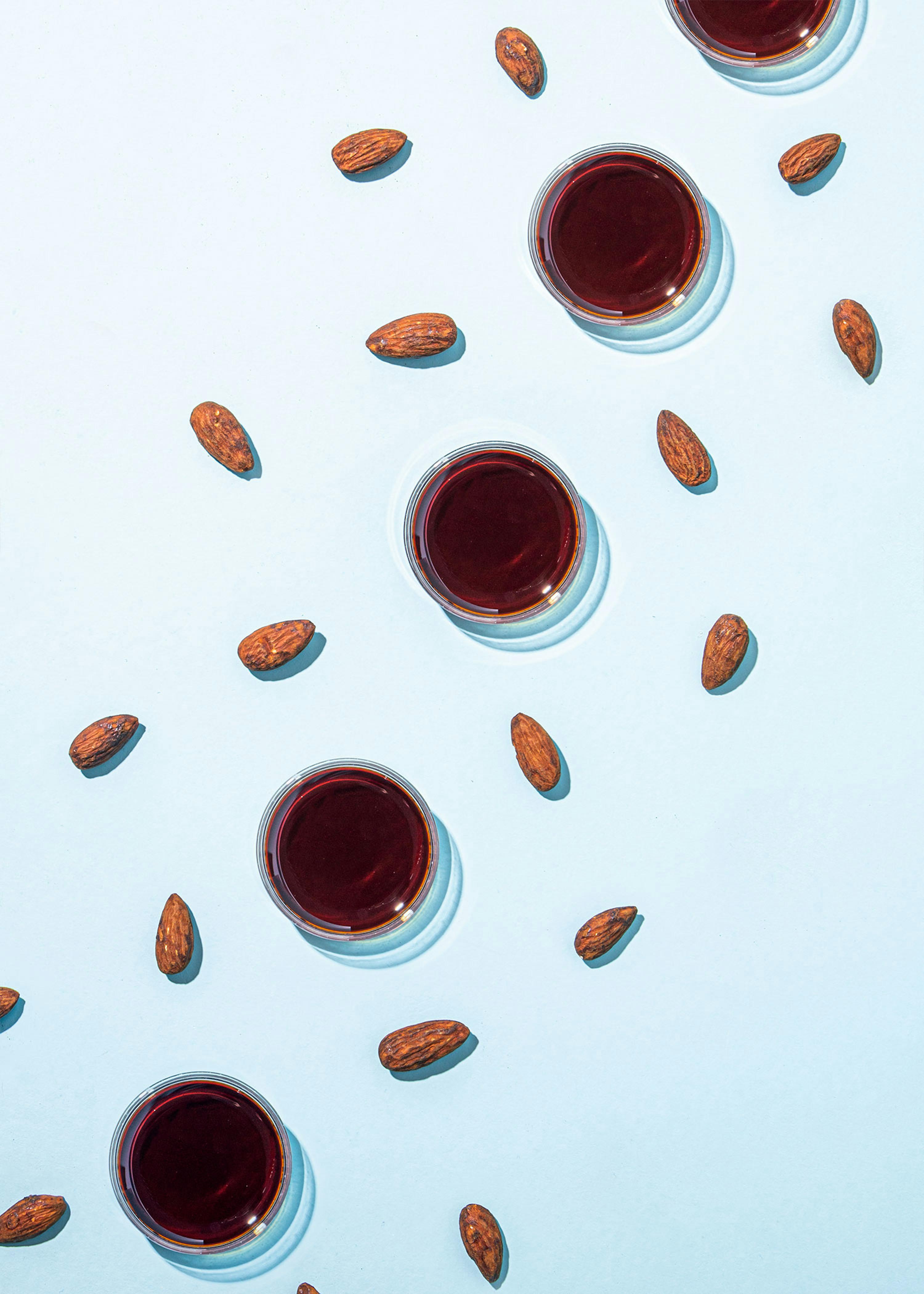 eine Reihe von Gläsern mit einer roten Flüssigkeit und Mandeln
