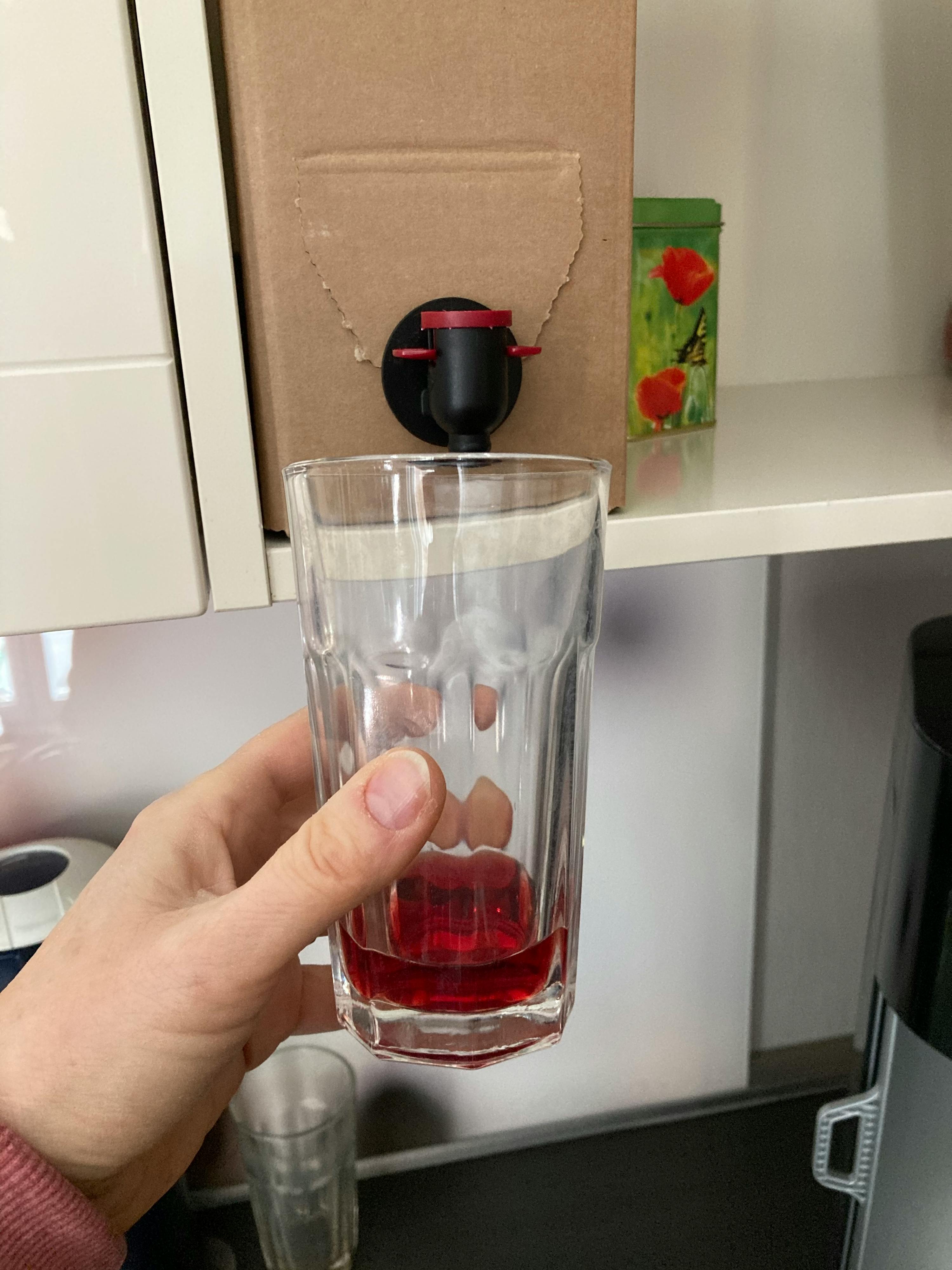 un uomo tiene in mano un bicchiere pieno di liquido rosso