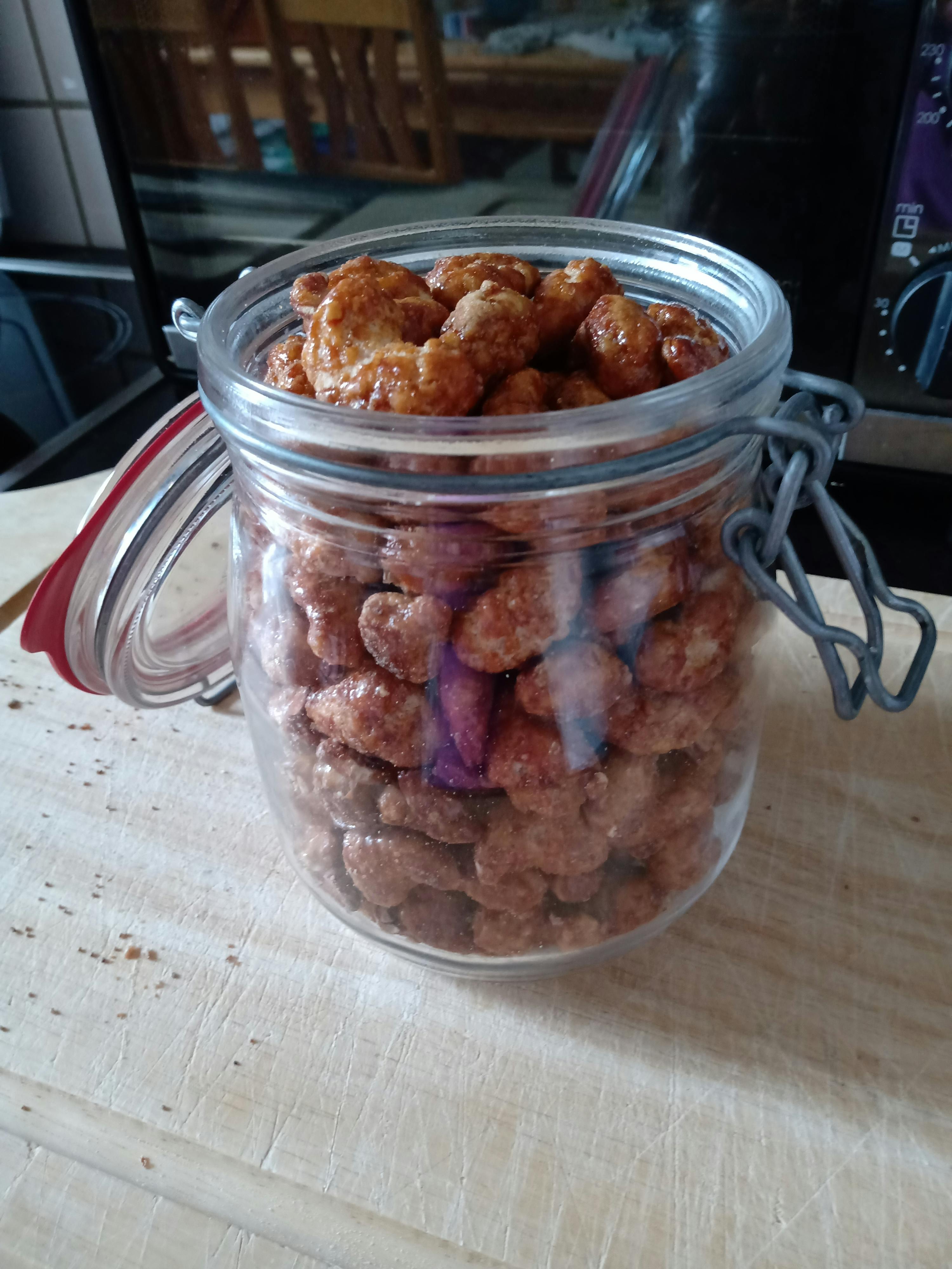 a glass jar filled with nuts sits on a cutting board