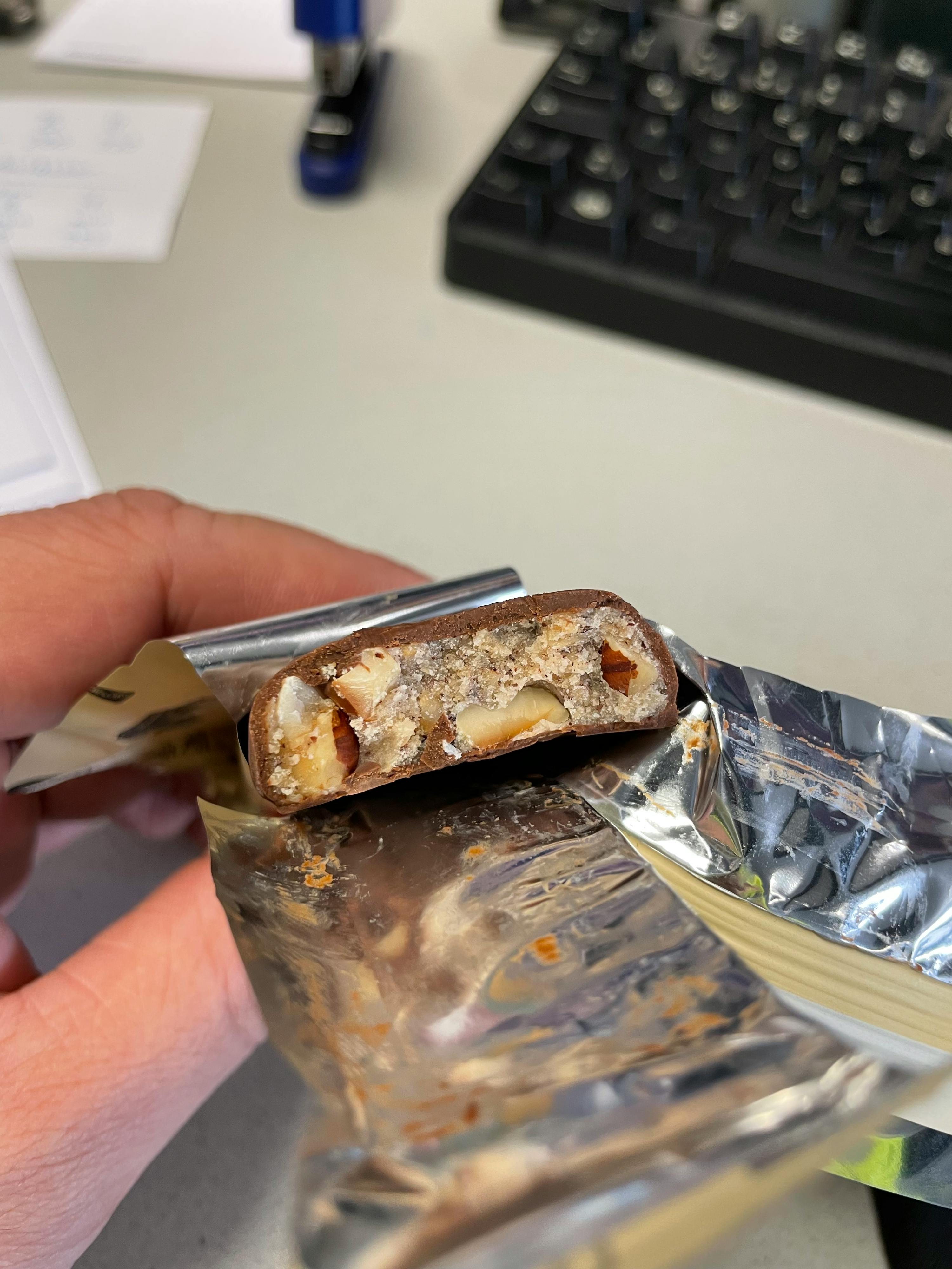 eine Person hält eine Schokoladenstange mit einem Stück genommen