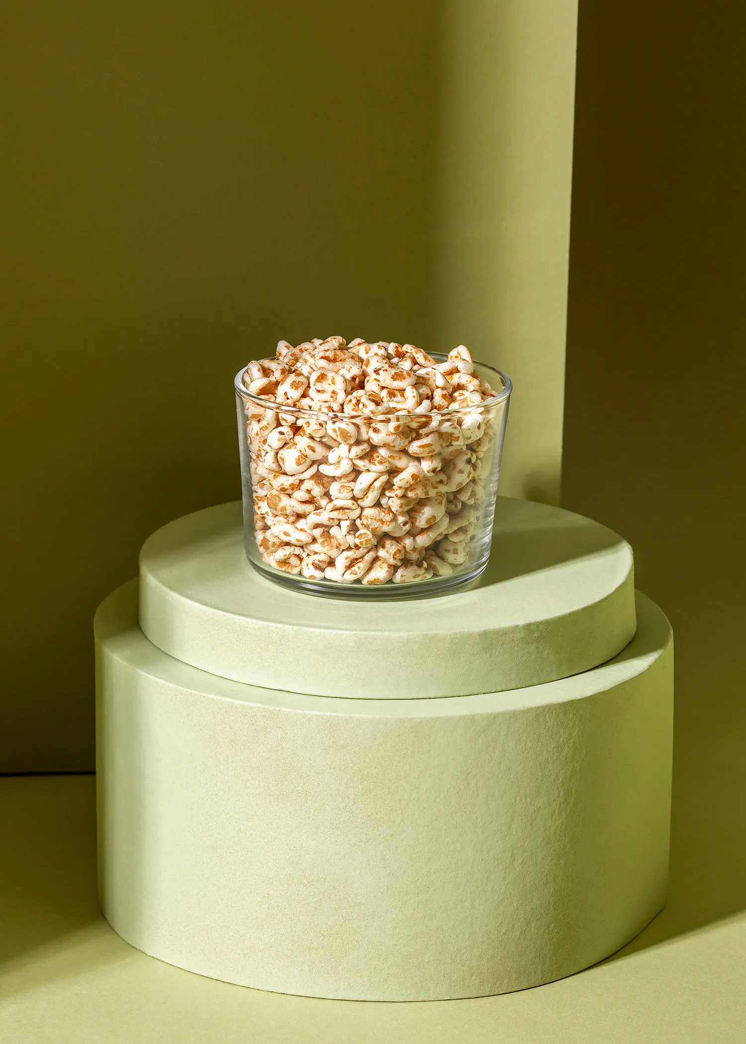 un bol en verre rempli de céréales est assis sur une base verte