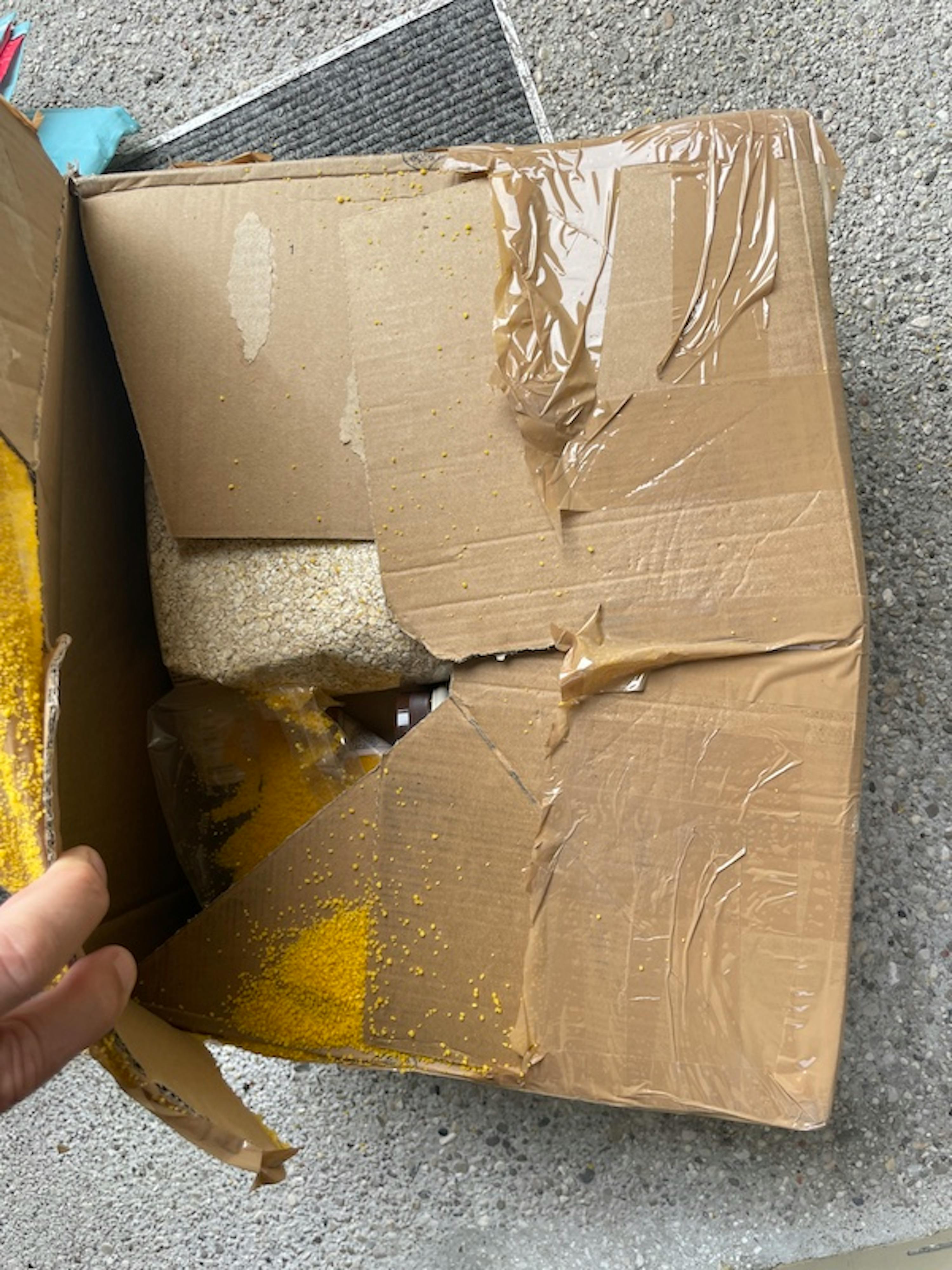 eine Person hält einen zerbrochenen Karton in der Hand