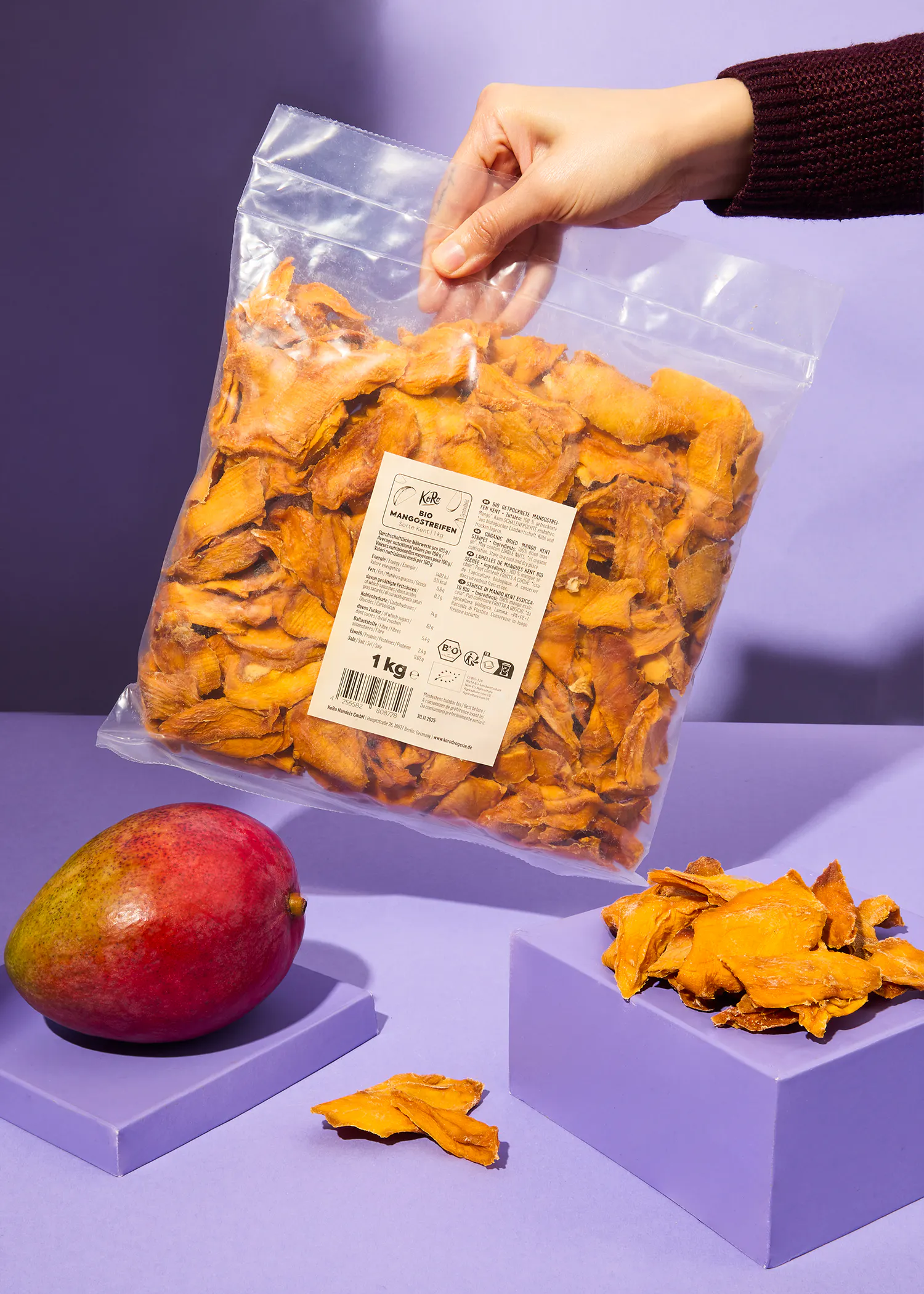 eine Person hält einen Plastiksack mit getrockneten Mangos in der Hand