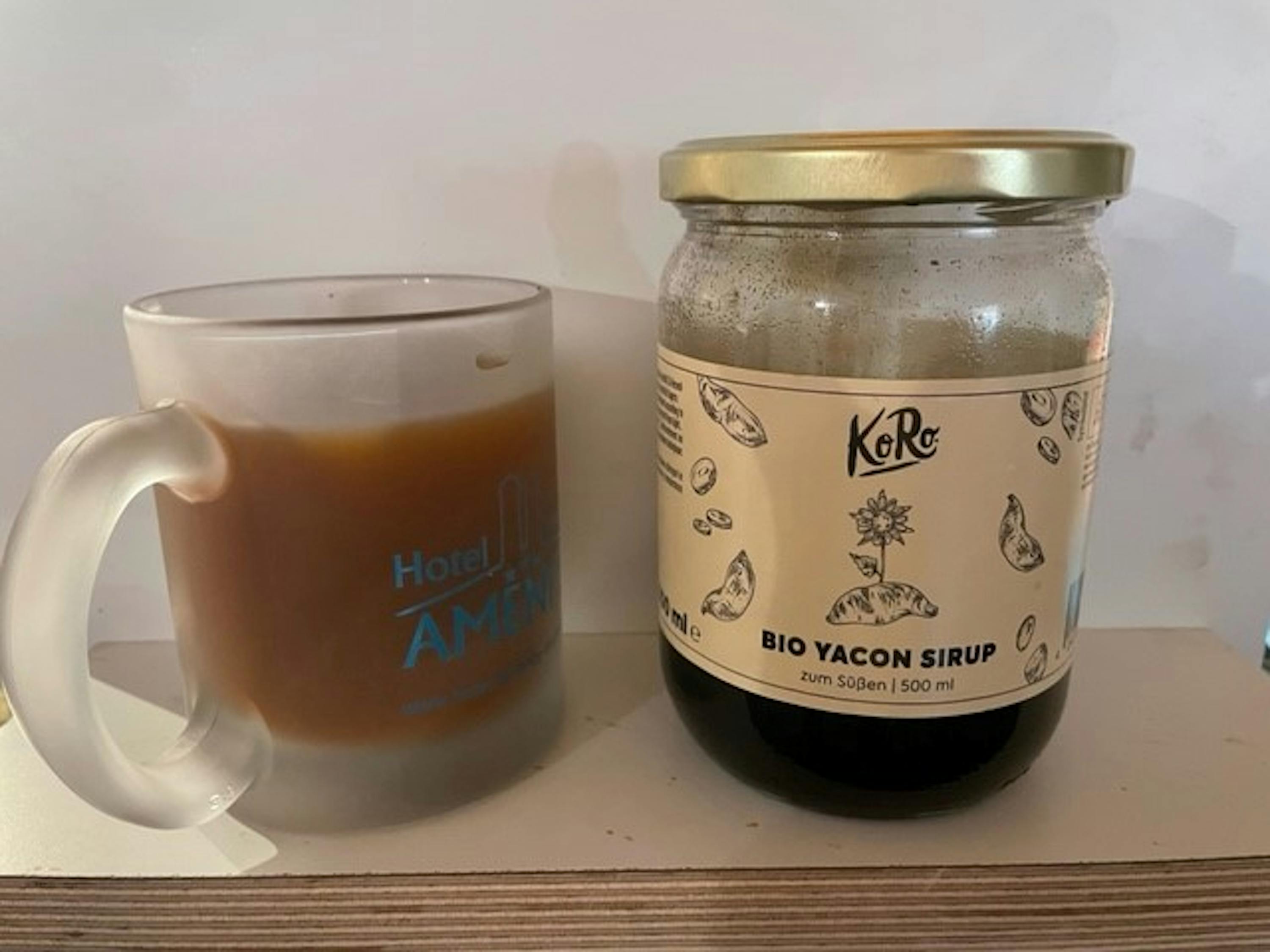 un bocal de sirop bio yacon est assis à côté d' une tasse de café .