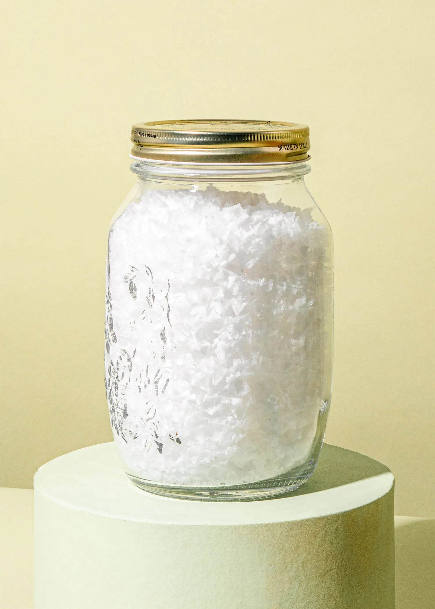 ein Glasgefäß mit einem goldenen Deckel gefüllt mit weißem Salz