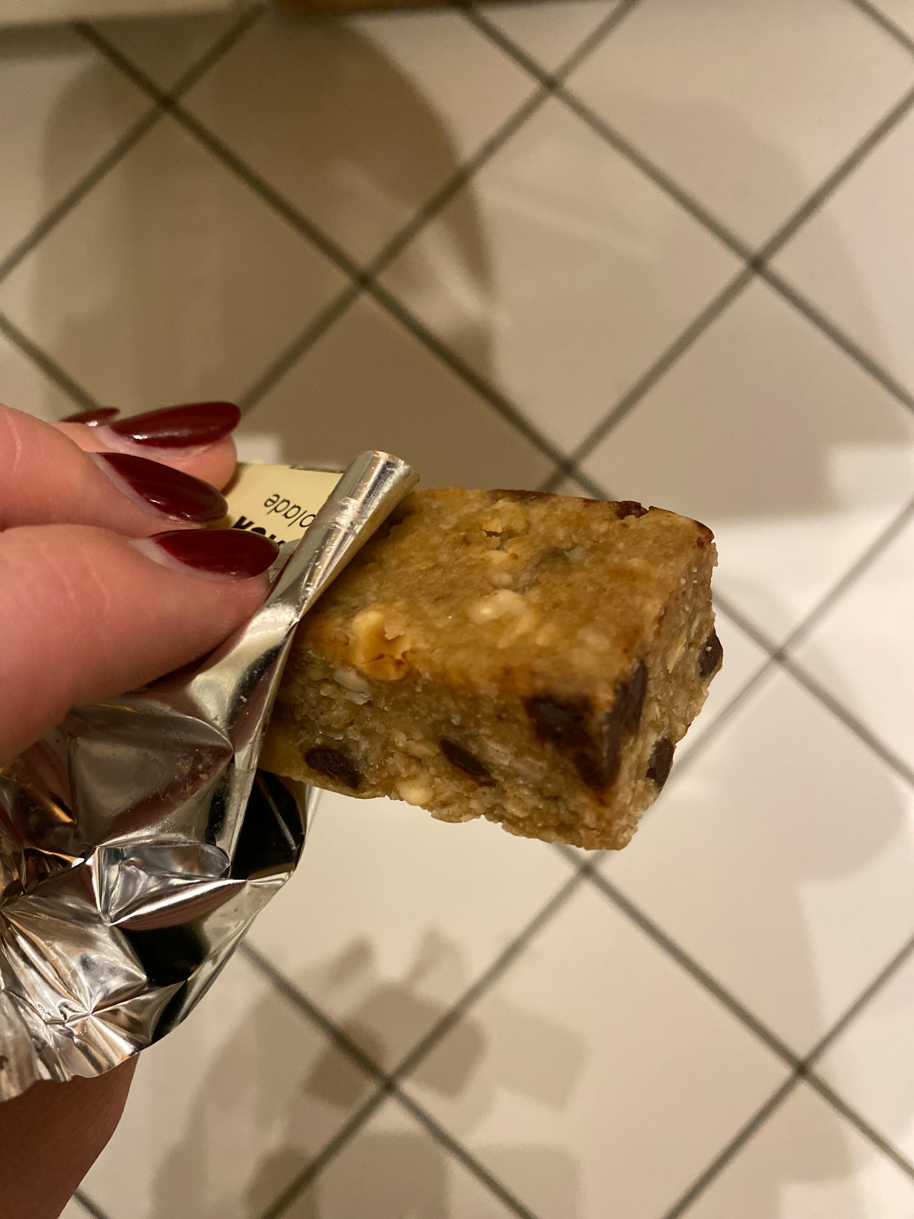 una persona tiene in mano una barretta di cioccolato e avena
