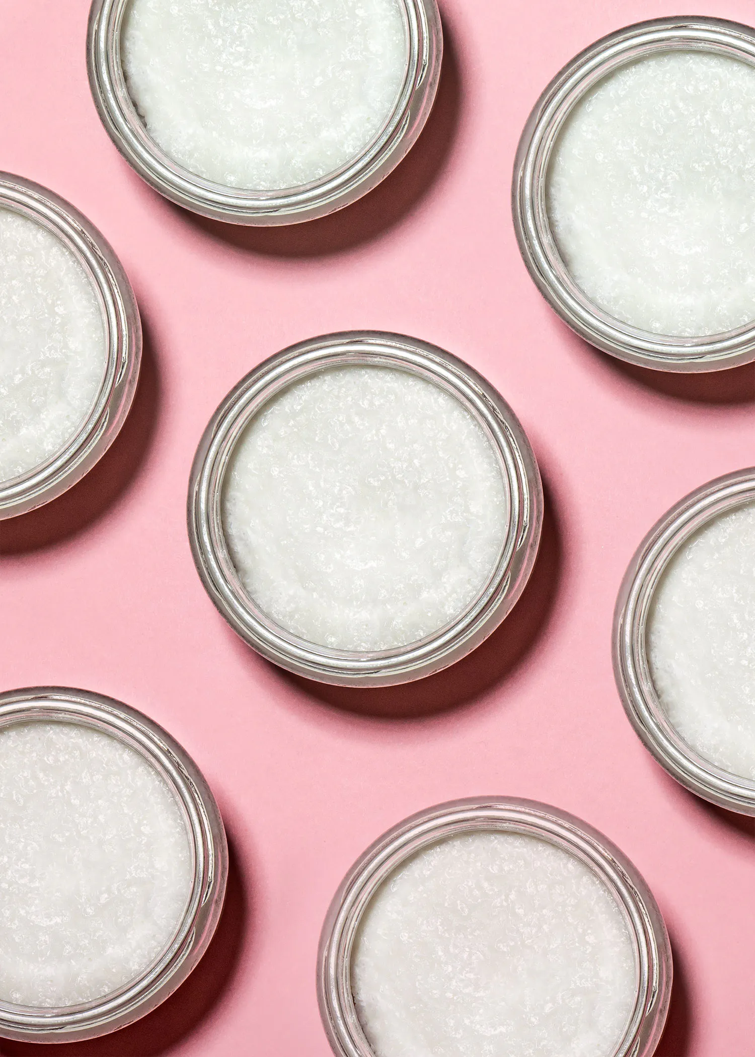 six bocaux en verre remplis d' une substance blanche sur fond rose