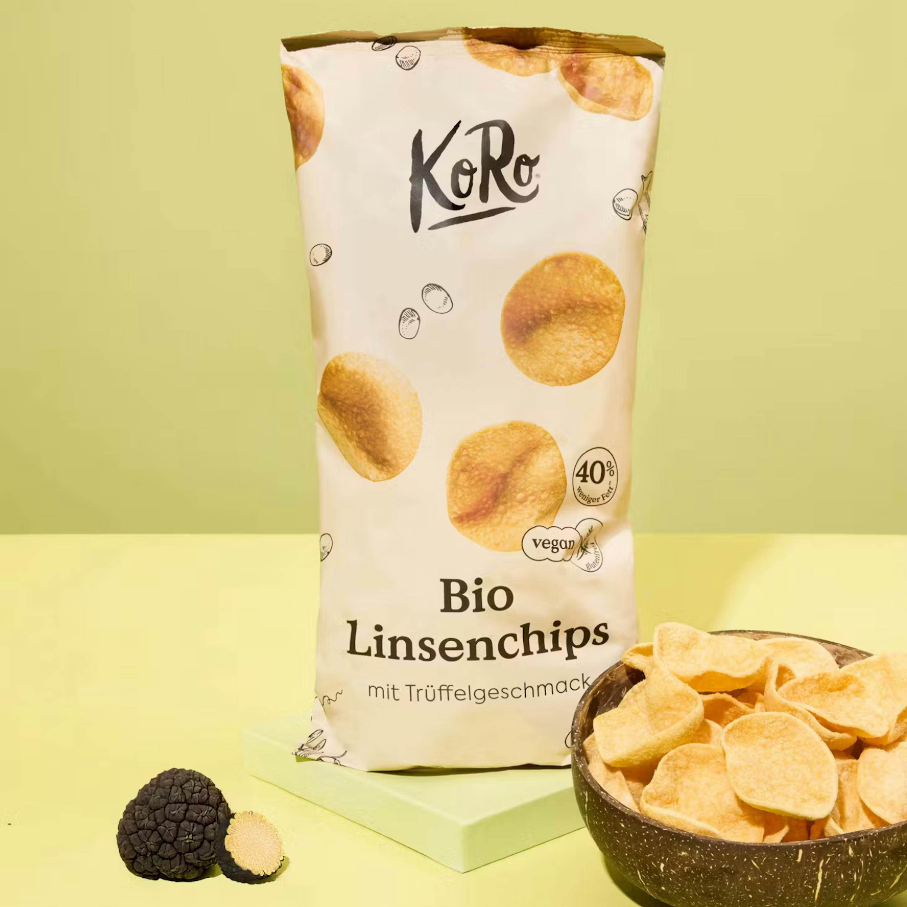 bolsa de chips de lentejas orgánicas sabor trufa de koro, un tazón de chips y una trufa negra entera y cortada sobre un fondo verde claro.