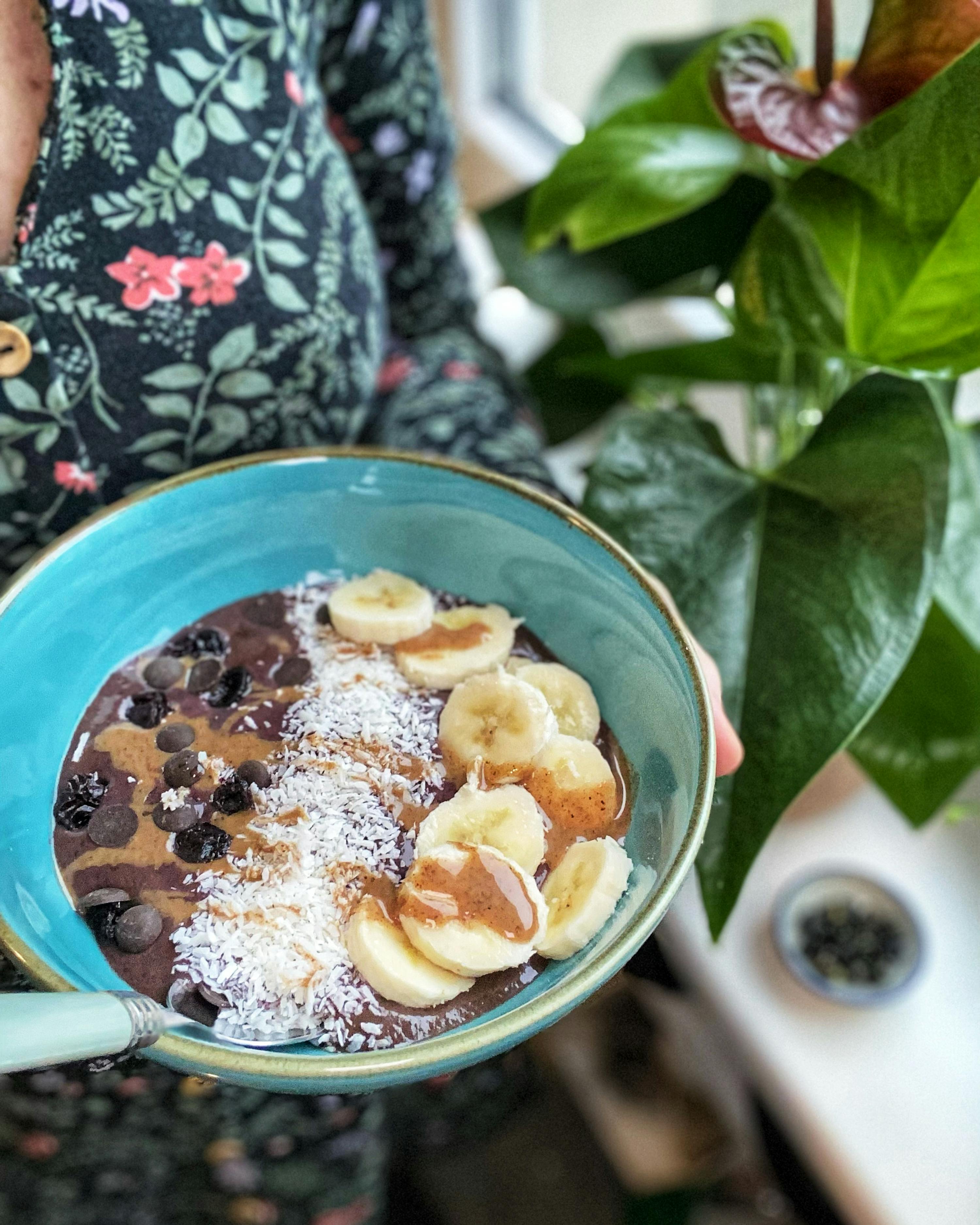 una persona tiene in mano una ciotola di cibo con banane e burro di arachidi